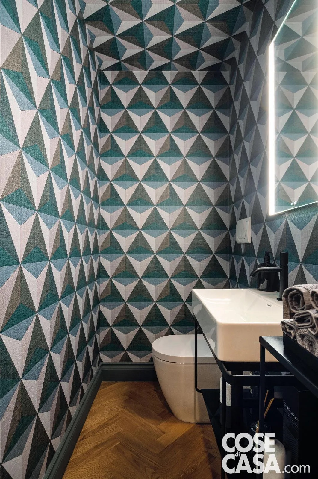 In questo piccolo bagno il rivestimento a parete e soffitto in carta da parati geometrica multicolore crea un effetto “scatola” avvolgente e magnetico. Gli arredi bianchi si stagliano netti, portando equilibrio visivo e lasciando alla grafica il ruolo da protagonista. In questo piccolo bagno il rivestimento a parete e soffitto in carta da parati geometrica multicolore crea un effetto “scatola” avvolgente e magnetico. Gli arredi bianchi si stagliano netti, portando equilibrio visivo e lasciando alla grafica il ruolo da protagonista.