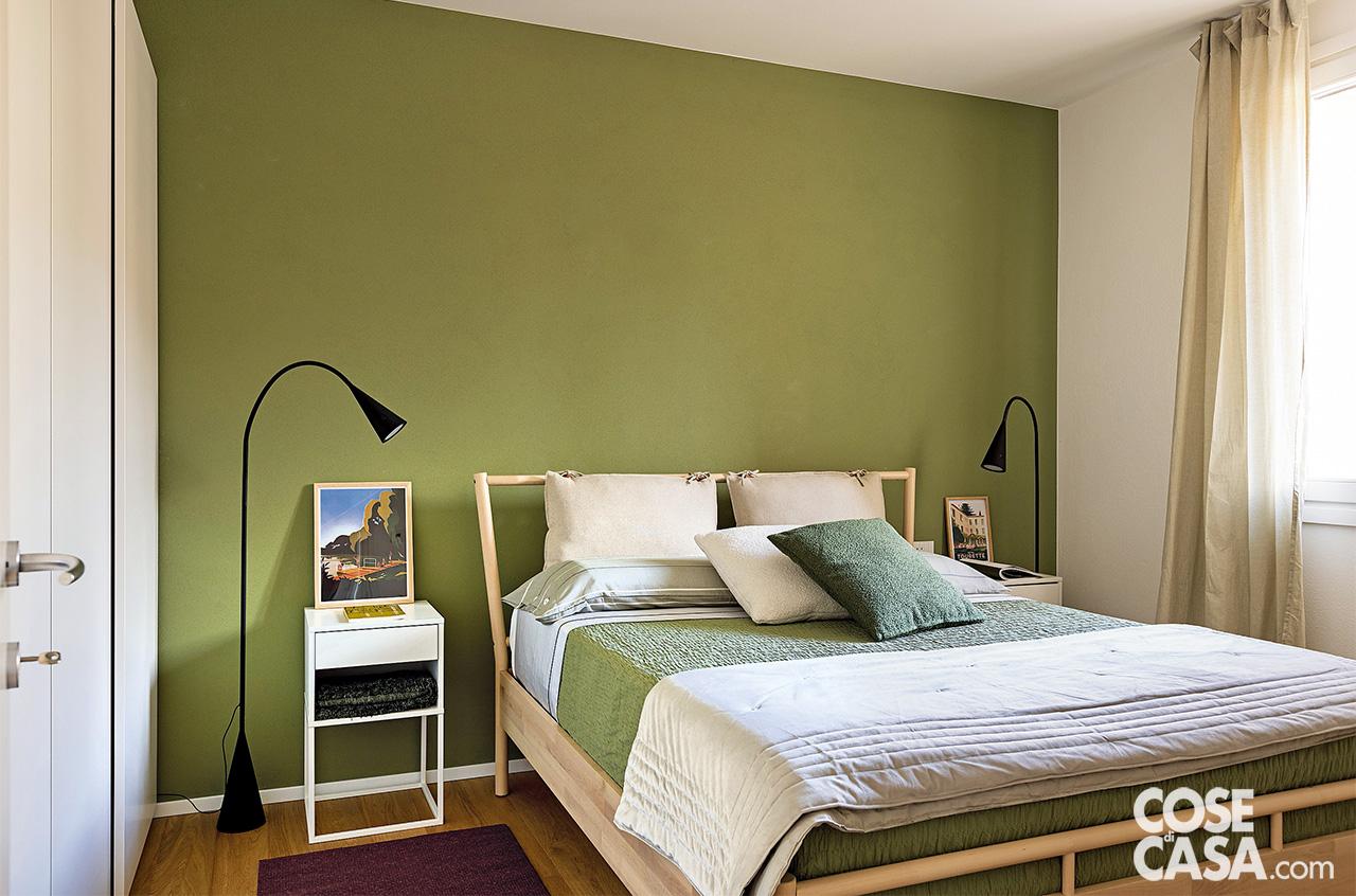 La parete dietro il letto è tinteggiata con smalto opaco verde oliva di Sikkens, il battiscopa è in legno laccato bianco. Il letto è il modello Bjorksnas, i comodini sono i Vikhammer, l'armadio in laccato bianco a sinistra è Pax, tutto di Ikea. Stessa produzione per le lampade nere da terra Delaktig by Tom Dixon. La passatoia a sinistra è di Kasthall. Lenzuola, federe, copriletto verde e trapuntina in velluto grigio sono tutti di Fazzini.