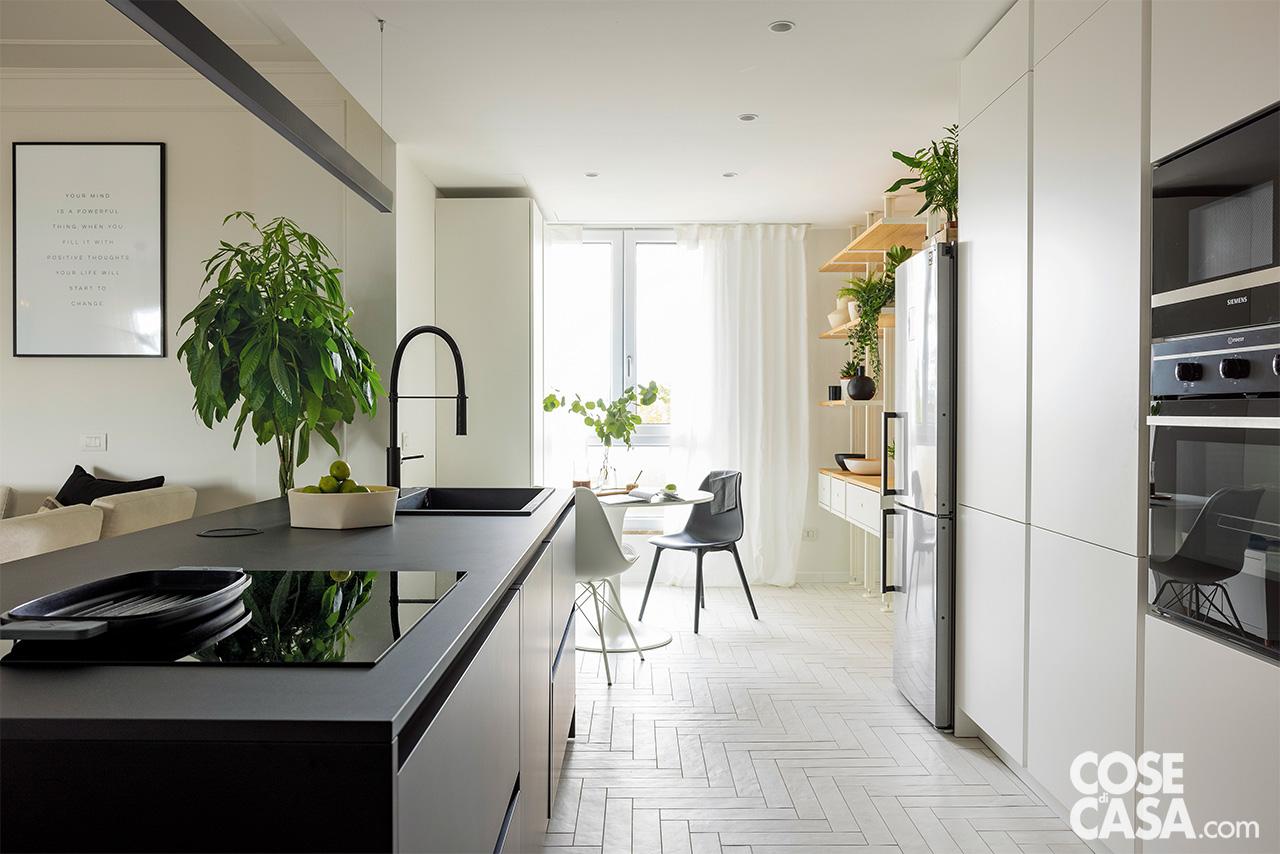 In cucina il programma della composizione è di Ar-Tre. Sull'isola centrale, il lavello da incasso Quadra 130 di Elleci è in granitek nero con miscelatore Light LIG179 di Paffoni. Il forno da incasso è di Siemens, il microonde di Indesit. Il pavimento è rivestito con piastrelle in formato 8 x 40 cm Clay 41 White di 41zero42. Nella zona della cucina il rivestimento a terra preesistente è stato sostituito. Dopo la gettata del nuovo massetto, sono stati posati listelli bianchi rettangolari di gres porcellanato che arrivano a filo del volume centrale dell'isola. La geometria a spina di pesce è stata scelta per richiamare quella tradizionale del parquet negli ambienti adiacenti. L'altezza della nuova soletta è stata calibrata in modo da evitare dislivelli.