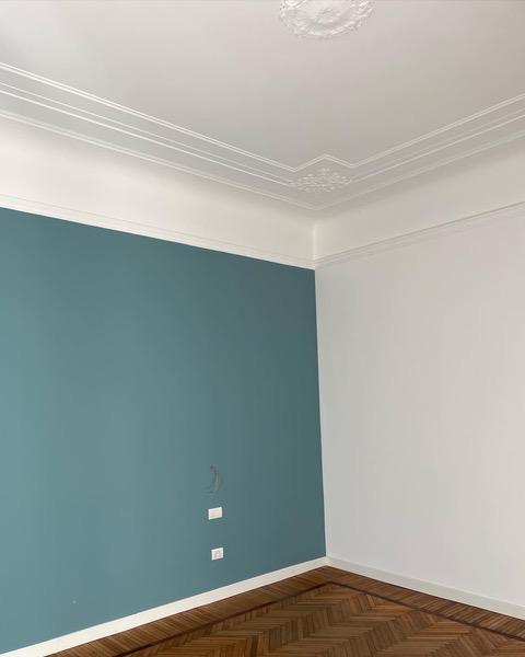 L’intervento si è concentrato su pochi elementi: pavimento e soffitto erano molto belli. Ma per aggiungere profondità e calore si è scelto di dipingere la parete dietro al letto, lasciando le altre bianche. E’ stata scelta una tonalità vicina all’ottanio, intensa ma riposante. Prima di dipingere sono state fatte due tracce laterali al letto per poter montare due lampade applique sopra i comodini: ecco un altro dettaglio che rende più cozy l’ambiente.