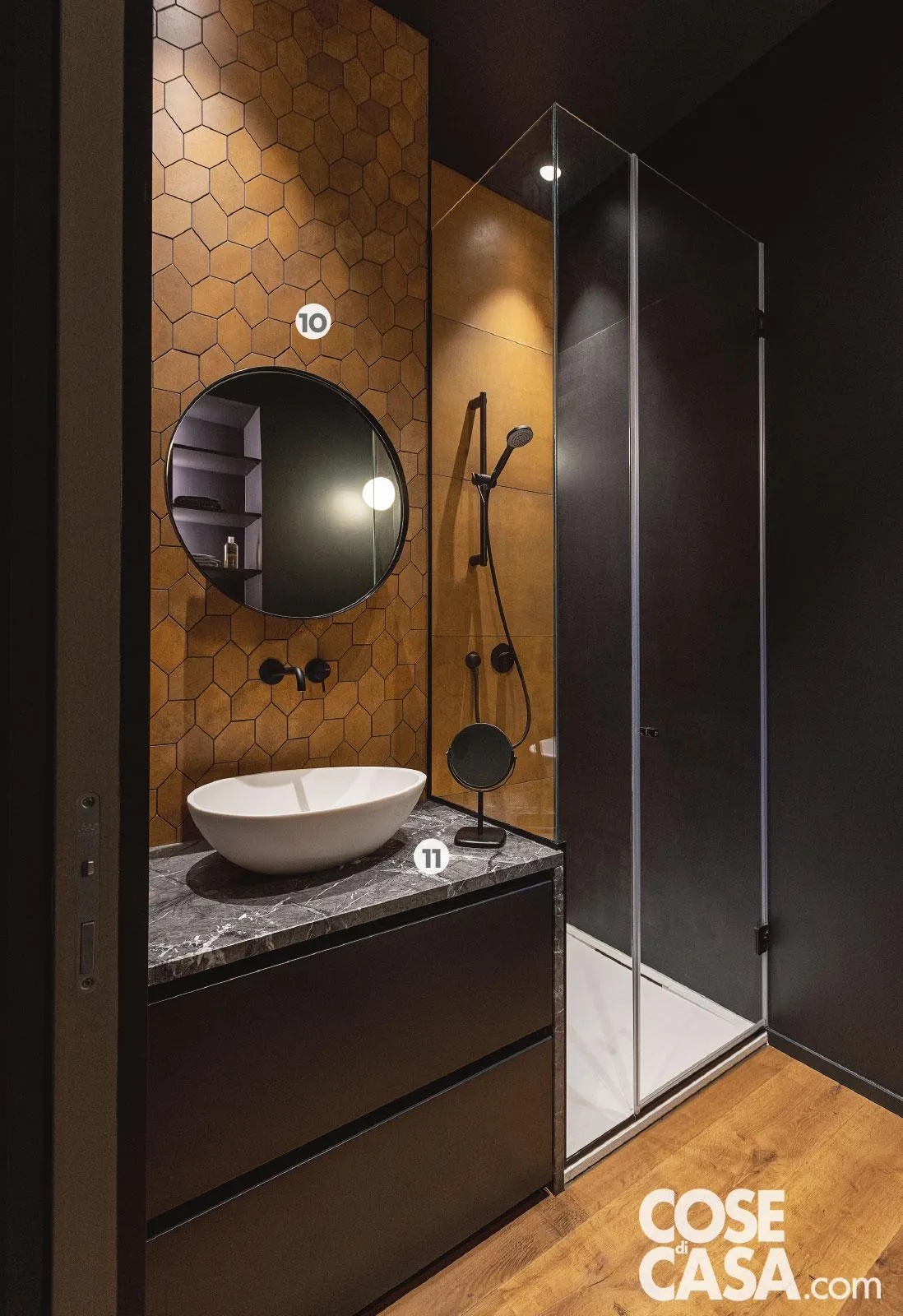 Parquet a terra e pareti rivestite in piastrelle esagonali color ocra e di grande formato nere conferiscono all'alternanza cromatica equilibrata, spezzata solo dai dettagli bianchi del piatto doccia e del lavabo. Parquet a terra e pareti rivestite in piastrelle esagonali color ocra e di grande formato nere conferiscono all'alternanza cromatica equilibrata, spezzata solo dai dettagli bianchi del piatto doccia e del lavabo.