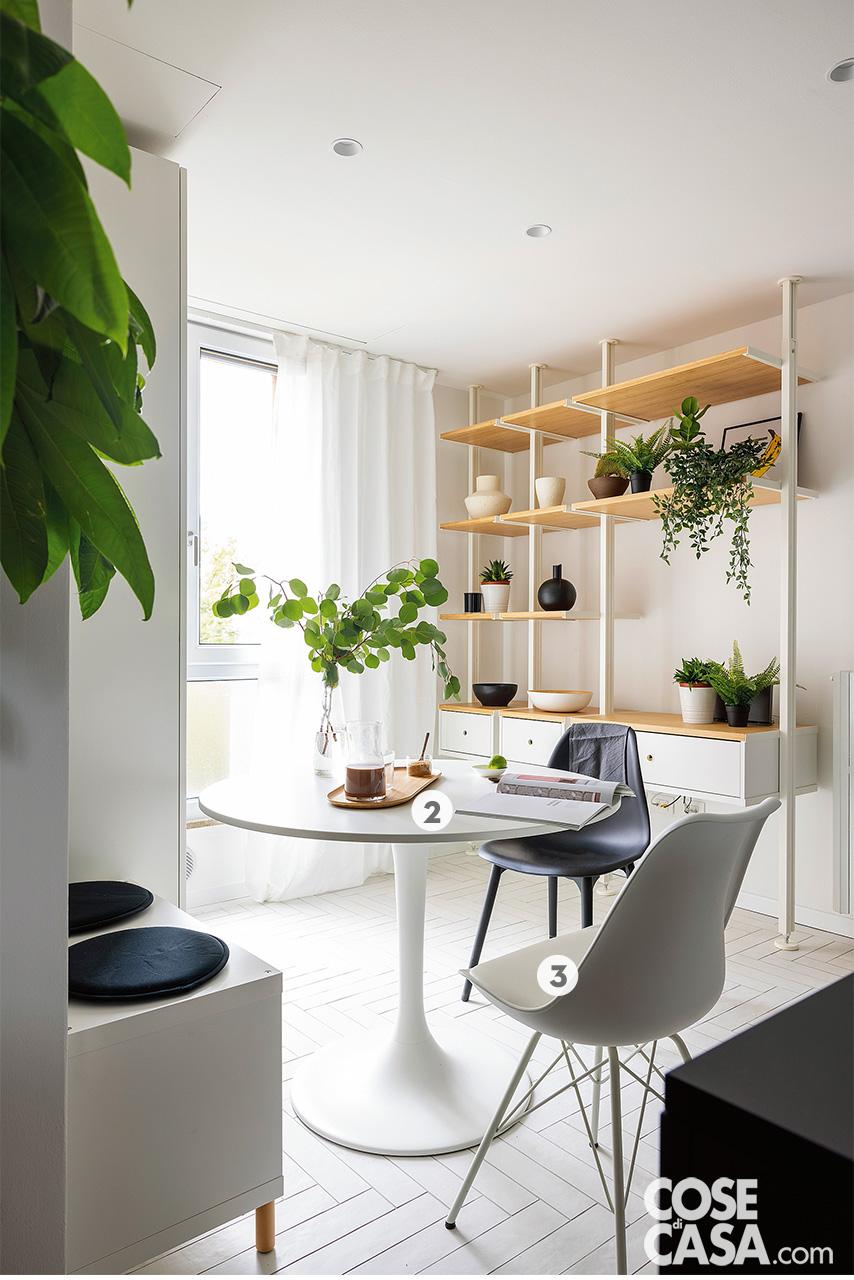 Nella zona pranzo della cucina, il tavolo rotondo bianco è il modello Docksta di Ikea; stessa produzione per la libreria bifacciale terra-cielo, modello Evarli. La sedia nera è la Scand di Sklum, la bianca è la Ralf di Kave Home. Vassoio appoggiato sul piano di Zara Home