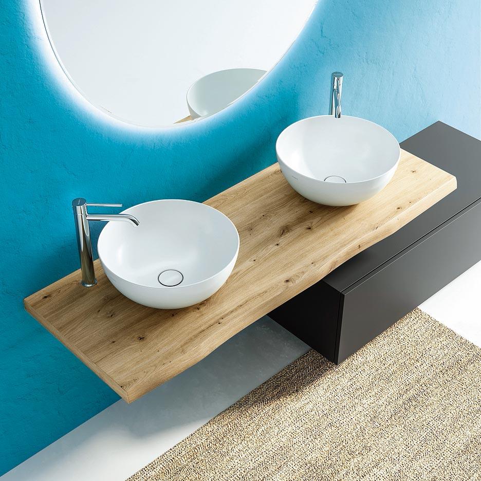 Sulla parete color ciano si stagliano top in rovere e lavabi bianchi della collezione Noemi di Ceramica Dolomite  (www.ceramicadolomite.it, prezzo  410 euro/cad. + Iva e disponibili anche nelle tinte bianco, nero opaco, grigio cemento, azzurro avio, rosa antico).