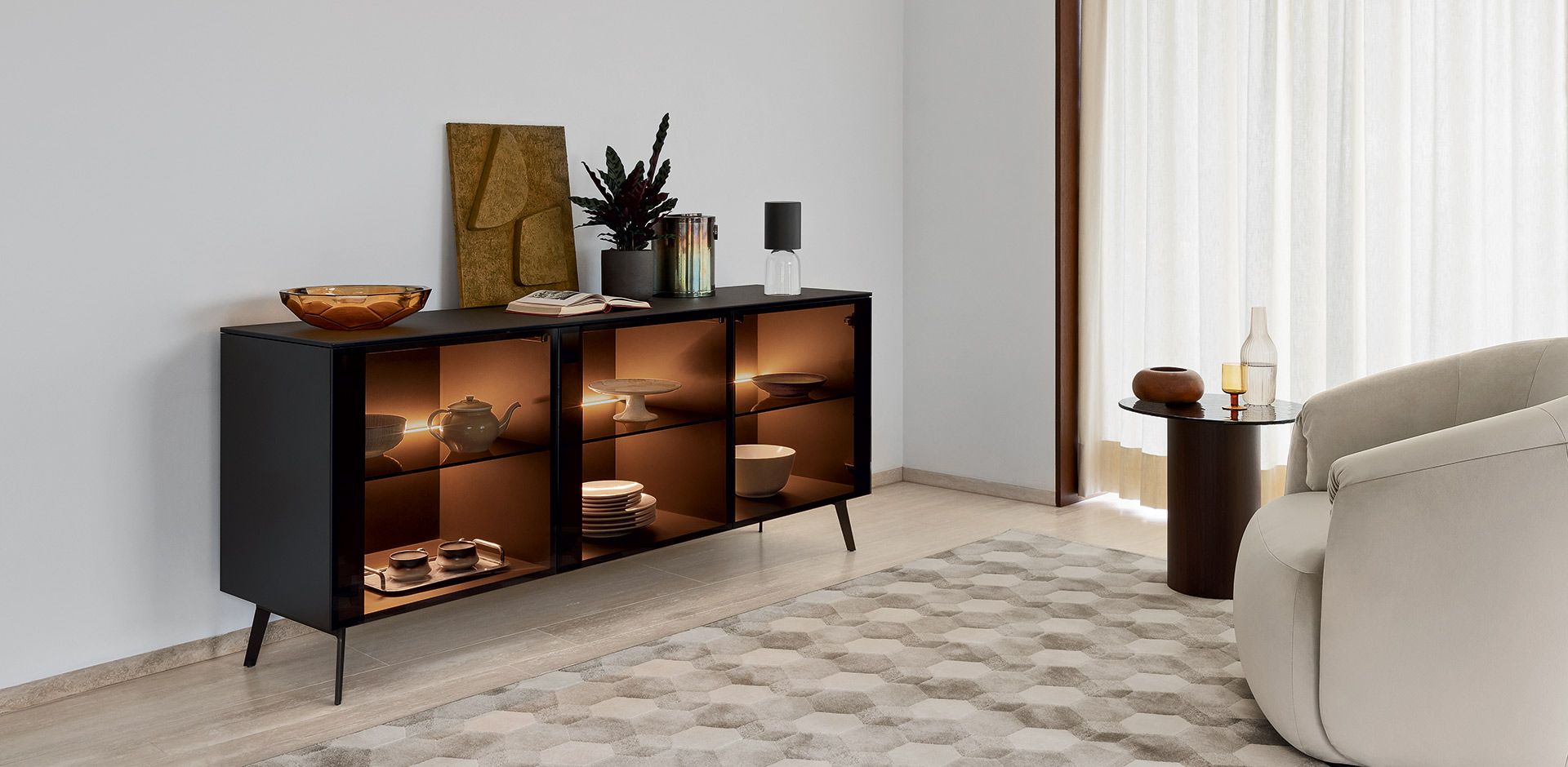 Ha tre ante in vetro bronzo trasparente la madia Universal di Calligaris che ha la struttura in legno laccato nero opaco; all'interno è possibile inserire una calda luce a led opzionale dimmerabile che trasforma la vetrina in una sorta di lampada scenografica. Il top è realizzato in accoppiato ceramica-vetro nella finitura marmo nero calacatta. Misura L 181 x P 50 x H 79 cm. Prezzo a partire da 3.115 euro. www.calligaris.com