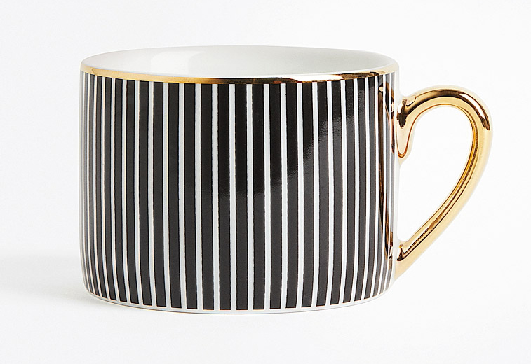È in porcellana la tazza di H&M Home con un raffinato decoro a righe nere arricchito da bordo e manico dorati. Misura Ø 9 x H 7 cm. Costa 4,99 euro. www.hm.com