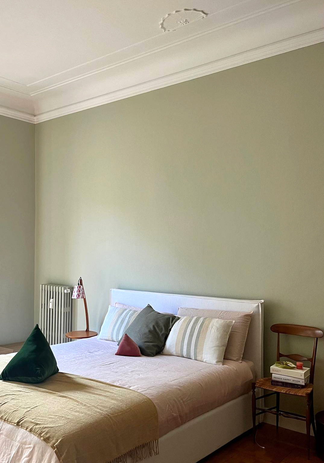 Una camera semplice ed essenziale, con le pareti dipinte color verde salvia, in cui la sedia chiavarina di famiglia è diventata il comodino. Dall’altro lato, c’è un tavolino vintage di recupero con lampada integrata. Una camera semplice ed essenziale, con le pareti dipinte color verde salvia, in cui la sedia chiavarina di famiglia è diventata il comodino. Dall’altro lato, c’è un tavolino vintage di recupero con lampada integrata.