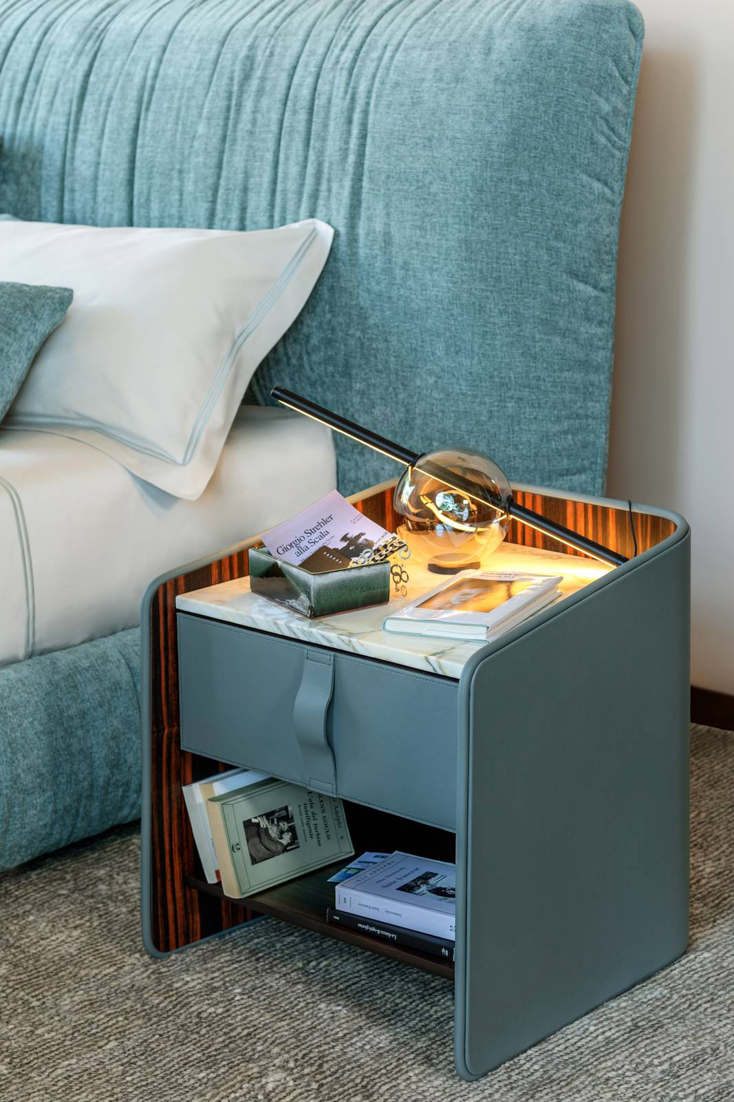 È disponibile in diverse altezze, per poter essere affiancato a qualsiasi tipologia di letto, dai più tradizionali a quelli con materassi importanti, il comodino Gentleman di Flou, designer Carlo Colombo; la struttura è realizzata in legno multistrato curvato rivestito esternamente in pelle e internamente in ebano con finitura opaca.  Il top superiore è in ebano. Misura L 58 x P 52 x H 49/57 cm. Prezzo a partire da 4.082 euro. https://www.flou.it