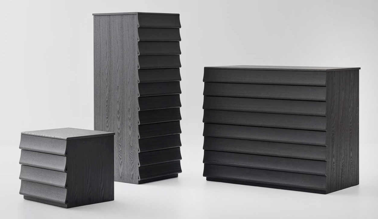 La collezione di mobili contenitore per la zona notte Rideaux di Bolzan è connotata da superfici sinuose e dalla quasi totale assenza di spigoli; il fronte ondulato, che sporge lateralmente dalla base, disegna una sequenza di drappeggi lignei. La struttura e i cassetti sono realizzati in legno di frassino tinto nelle tonalità naturali Terra di Siena, azzurro, indaco, nero e grigio. Il settimino misura L 51,5 x P 54 x H 132 cm. La cassettiera misura L 105,5 x P 58 x H 89,5 cm. Il comodino misura L 51,5 x P 44 x H 47 cm. https://www.bolzan.com – Fuorisalone, BolzanSpace - Via Mercato 3, Milano.