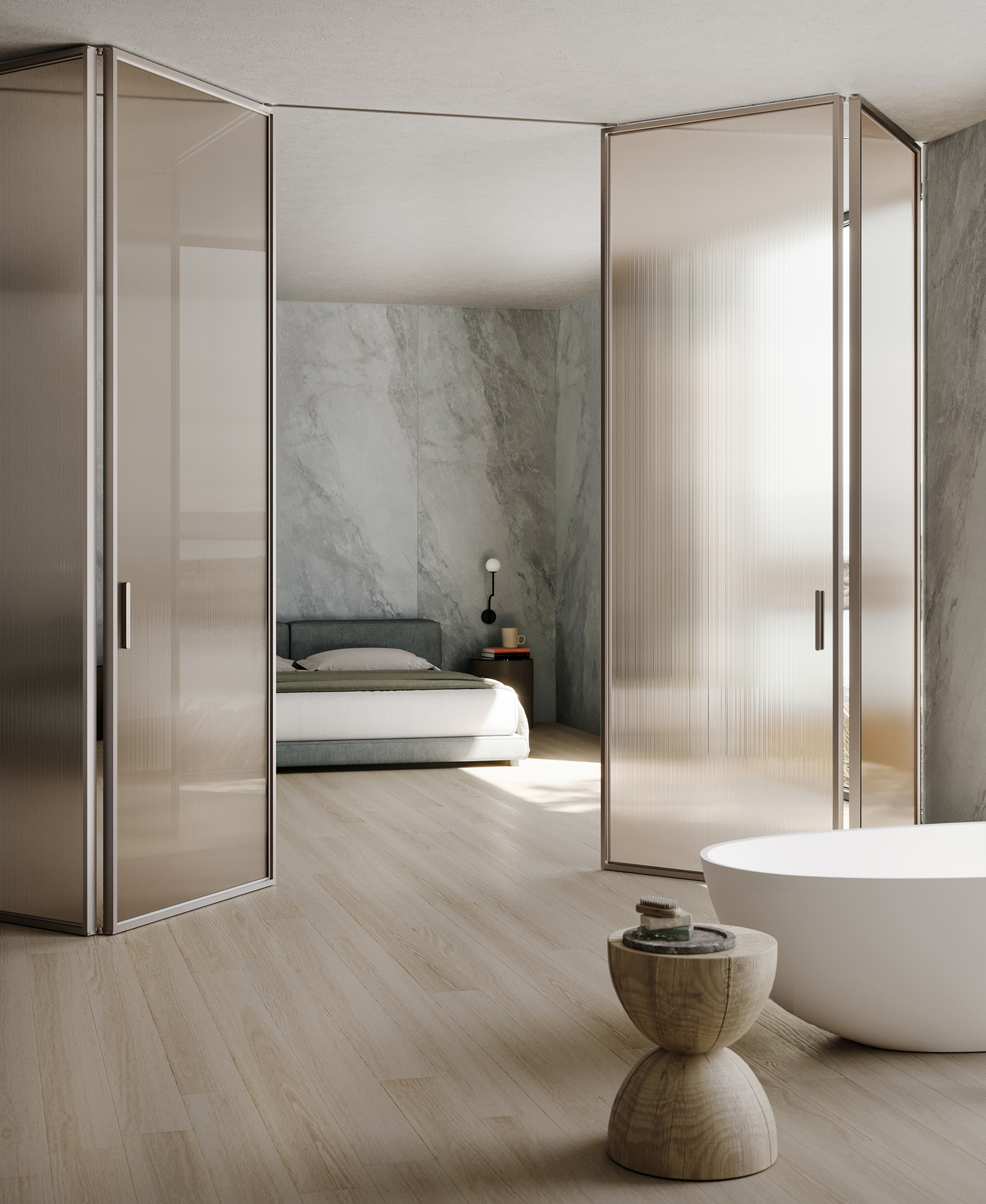 La porta interna L7 Bi-folding di Lualdi con le ante a libro nella raffinata texture Mini Flutes, realizzata in vetro cannettato, nella variante di colore bronzo satinato, permette di definire l'intimità e i diversi spazi del vivere, dalla casa all'ufficio passando per l' hotellerie; i profili e le maniglie in alluminio nella versione Titanium, che aggiunge un tocco di eleganza e calore, senza compromettere la leggerezza complessiva. https://www.lualdi.com - Salone del Mobile, padiglione 9, stand H11.