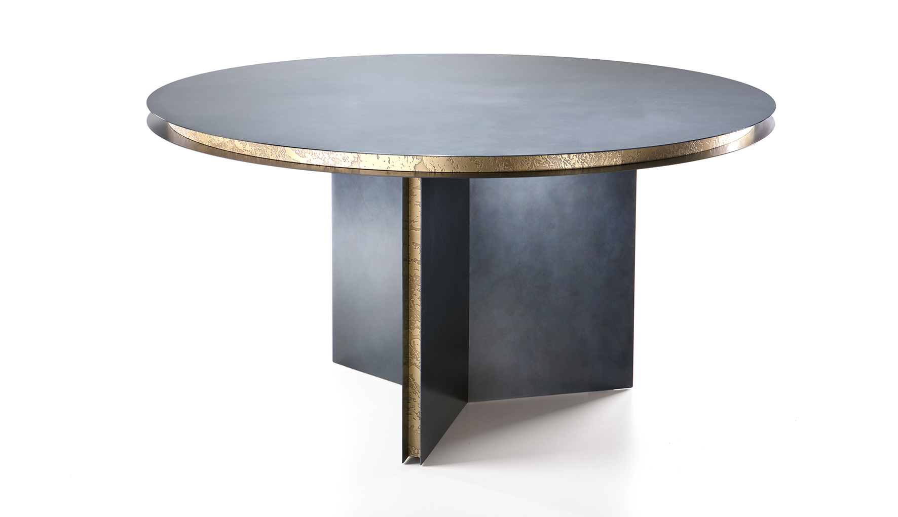 Il tavolo Folio Round di De Castelli ha il grande top rotondo caratterizzato da ricercati dettagli costruttivi che danno vita a giochi di luce sulla superficie. È composto da due lastre tonde in acciaio DeDeep che accolgono una fascia arretrata in ottone DeErosion e definiscono il piano. La base di appoggio è studiata per garantire il giusto comfort quando seduti. Misura Ø 148 x H 75 cm. https://www.decastelli.com - Salone del Mobile, padiglione 24, stand B01-B02.