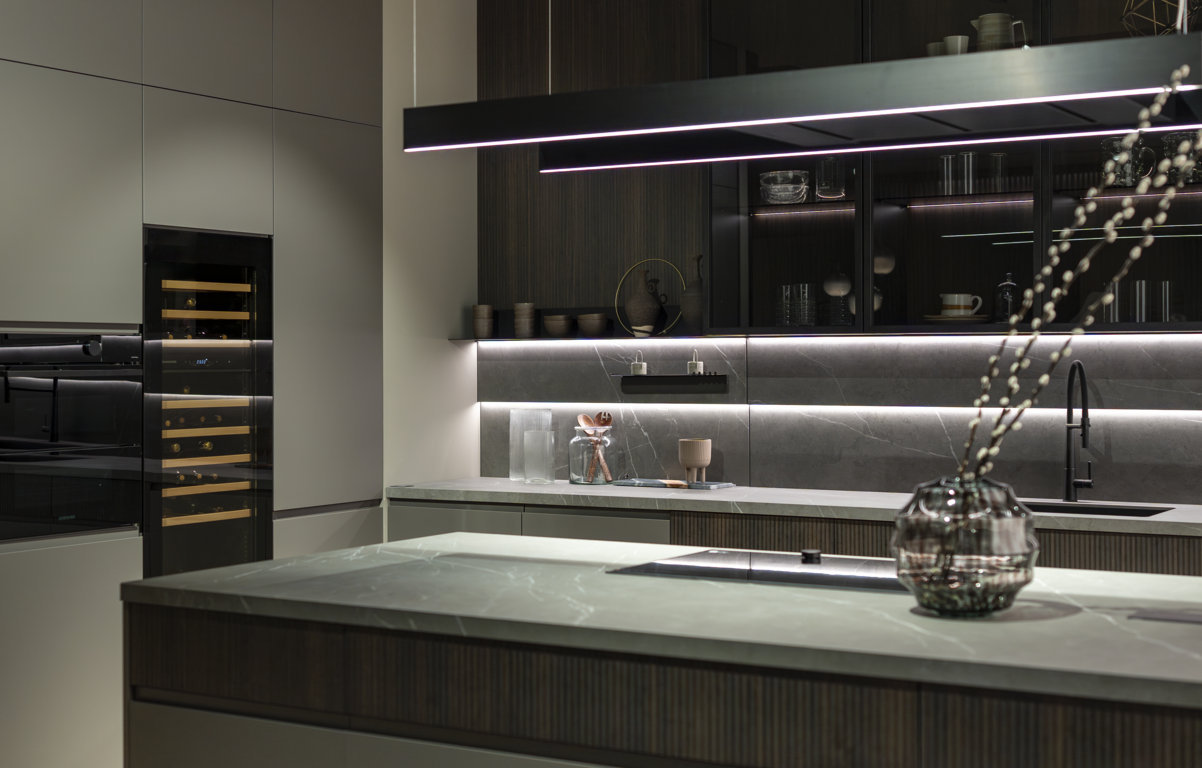 A destra e a sinistra delle vetrine Vogue, sono posizionate le mensole Air in alluminio nero, montate su pannelli in laminato riga termocotto.
Le colonne accolgono tutti gli elettrodomestici a incasso, cantina vini compresa, e sono sempre in PET opaco lavagna.