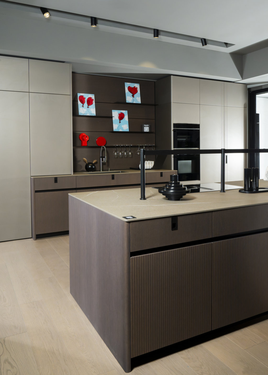 Le colonne in nicchia della collezione Time sono in laccato metallizzato platino con la maniglia Brera in verticale, mentre sui cassetti è collocata la maniglia Brera nella variante Plus.
Il luminoso tono di grigio è abbinato all’Asia impiallacciato noce delle basi, sia dell’isola sia a parete, e della schiena della boiserie LAB, dotata di mensole e portacalici in alluminio nero. Maniglie Brera, ponte Tuttotondo sull’isola, zoccoli e gole sono in alluminio nero.