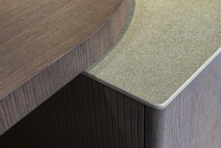 Particolare dalla collezione Arco proposta da Arredo3 per addolcire i fianchi di ogni modulo. Ben visibile anche la lavorazione cannettata dell’impiallacciato noce, il top in Laminam® Pietra Piasentina Taupe fiammata e l’appoggio del piano snack Arco sull’isola, anch’esso realizzato in Asia impiallacciato noce