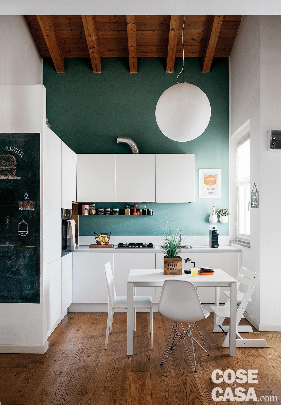 La zona cottura è evidenziata dallo sfondo della parete, tinteggiata a tutta altezza in una tonalità verde scuro che fa risaltare i profili total white dei diversi elementi d'arredo. La disposizione dei pensili sottolinea la doppia altezza del volume in corrispondenza della cucina. Nella zona pranzo il tavolo allungabile di forma quadrata, con gambe in alluminio e piano in nobilitato, è il modello More di Pedrali. Le sedie, una diversa dall'altra, sono accomunate dalla finitura total white: il seggiolone trasformabile a destra è Tripp Trapp di Stokke, la centrale è la DSR di Vitra, design Charles & Ray Eames, quella a sinistra è la Norma di Arper. La lampada a sospensione sferica è il modello Moon di Davide Groppi. Progetto arch. Matteo Guerini - MAD14 Studio, Crema, Tel. 0373/86484, www.mad14studio.it. Foto Studio Roy. Stylist Chiara Dal Canto. La zona cottura è evidenziata dallo sfondo della parete, tinteggiata a tutta altezza in una tonalità verde scuro che fa risaltare i profili total white dei diversi elementi d'arredo. La disposizione dei pensili sottolinea la doppia altezza del volume in corrispondenza della cucina. Nella zona pranzo il tavolo allungabile di forma quadrata, con gambe in alluminio e piano in nobilitato, è il modello More di Pedrali. Le sedie, una diversa dall'altra, sono accomunate dalla finitura total white: il seggiolone trasformabile a destra è Tripp Trapp di Stokke, la centrale è la DSR di Vitra, design Charles & Ray Eames, quella a sinistra è la Norma di Arper. La lampada a sospensione sferica è il modello Moon di Davide Groppi. Progetto arch. Matteo Guerini - MAD14 Studio, Crema, Tel. 0373/86484, www.mad14studio.it. Foto Studio Roy. Stylist Chiara Dal Canto.