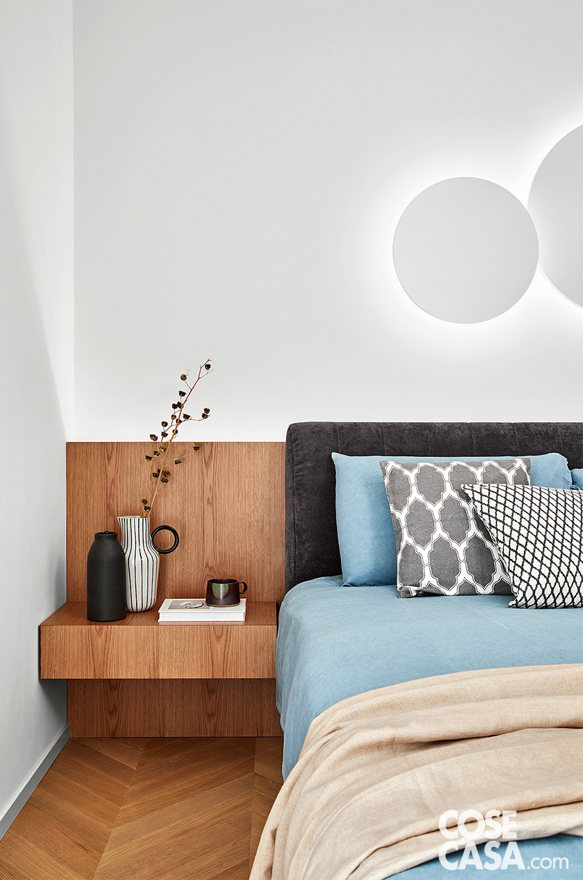 camera da letto con comodino in legno e letto tessile grigio; biancheria sui toni dell'azzurro e cuscini d'arredo bianchi e grigi camera da letto con comodino in legno e letto tessile grigio; biancheria sui toni dell'azzurro e cuscini d'arredo bianchi e grigi