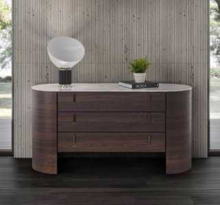 Il comò Charlie di Conte ha una linea sinuosa e una struttura curvata realizzata in legno massello; il piano ovale in marmo bianco è disponibile anche in vetro o in legno. Le maniglie verticali dei tre cassetti sono in metallo verniciato o Ottone Brunito. Misura L 160 x P 61 x H 82 cm. Prezzo a partire da 5.882 euro. www.contecasa.it