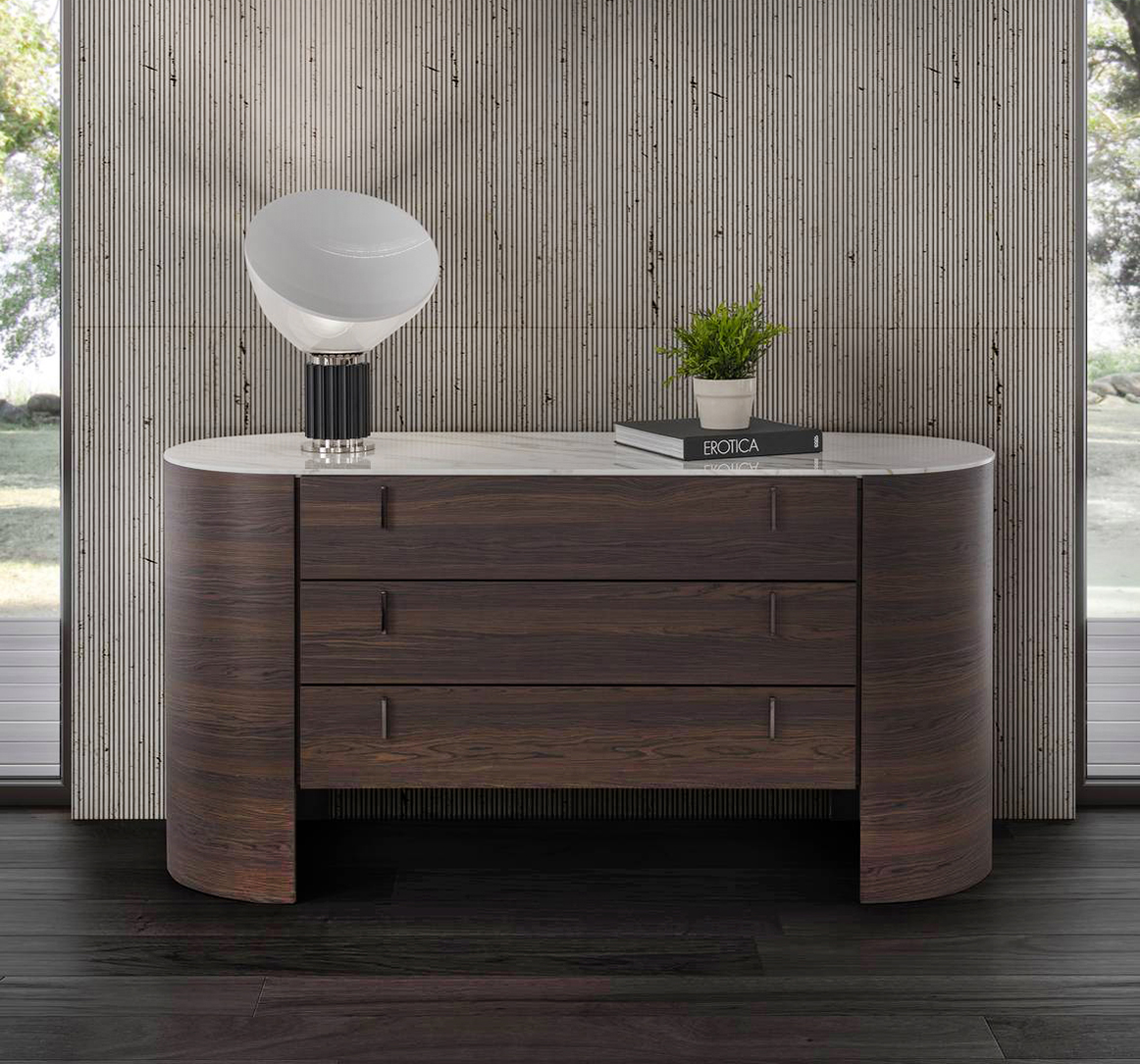 Il comò Charlie di Conte ha una linea sinuosa e una struttura curvata realizzata in legno massello; il piano ovale in marmo bianco è disponibile anche in vetro o in legno. Le maniglie verticali dei tre cassetti sono in metallo verniciato o Ottone Brunito. Misura L 160 x P 61 x H 82 cm. Prezzo a partire da 5.882 euro. www.contecasa.it