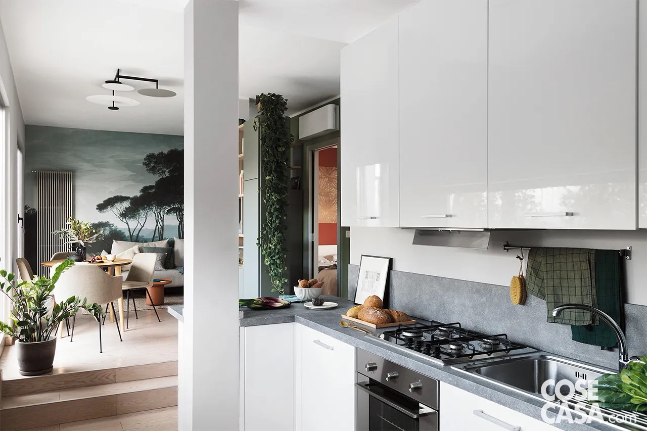 Il living open space è il fulcro di questo appartamento, inondato dalla luce di due portefinestre che affacciano su un ampio terrazzo. L’ambiente è anche il punto focale del progetto d’interior che si richiama al Feng Shui (dal cinese feng=vento o soffio, shui=acqua) perché proprio qui è stato individuato il “baricentro” della casa, uno degli elementi base secondo questa scuola. Il locale è scandito in tre zone: pranzo e conversazione occupano una superficie rialzata di due gradini rispetto all’area d’ingresso destinata alla cucina. Del soggiorno si rende protagonista la parete di fondo rivestita con una carta da parati a motivi naturalistici, Pine Trees di Les Dominotiers, in dialogo con le piante d’interni: specie viventi, in grado di fornire energia, purificare l’aria, portare protezione, equilibrio, tranquillità. Davanti, il divano letto Malloy di Innovation Living è affiancato dal radiatore Wind di Brem e servito dal tavolino Oban Table di Moooi. Il living open space è il fulcro di questo appartamento, inondato dalla luce di due portefinestre che affacciano su un ampio terrazzo. L’ambiente è anche il punto focale del progetto d’interior che si richiama al Feng Shui (dal cinese feng=vento o soffio, shui=acqua) perché proprio qui è stato individuato il “baricentro” della casa, uno degli elementi base secondo questa scuola. Il locale è scandito in tre zone: pranzo e conversazione occupano una superficie rialzata di due gradini rispetto all’area d’ingresso destinata alla cucina. Del soggiorno si rende protagonista la parete di fondo rivestita con una carta da parati a motivi naturalistici, Pine Trees di Les Dominotiers, in dialogo con le piante d’interni: specie viventi, in grado di fornire energia, purificare l’aria, portare protezione, equilibrio, tranquillità. Davanti, il divano letto Malloy di Innovation Living è affiancato dal radiatore Wind di Brem e servito dal tavolino Oban Table di Moooi.