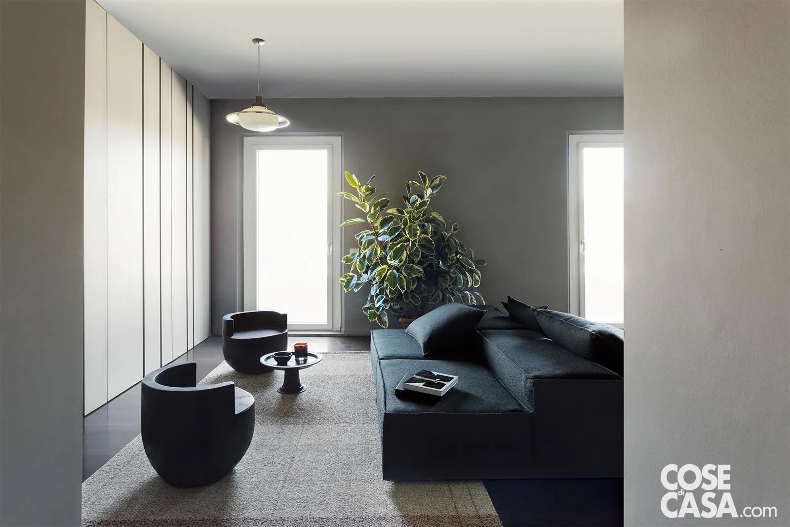 Doppio divano a centro stanza, che divide l’ambiente. Nell’ampio soggiorno con due portefinestra gemelle, sul grande tappeto a riquadri di lana in vari toni di grigio (di Kasthall, kasthall.com) domina al centro il maxi divano componibile realizzato su disegno dei progettisti. È abbinato a due poltroncine (Albizia Chair – design Mauro Mori – di Cappellini, cappellini.com) e a un tavolino vintage in legno, souvenir di uno dei tanti viaggi del padrone di casa. Foto: Studio Roy. Styling: Lidia Elisa Covello. Progetto: META- Interior Architecture Milano (arch. Caterina Marazzi, arch. Luca Miserocchi) Milano meta-milano.com. Clicca qui per vedere tutta la casa. Doppio divano a centro stanza, che divide l’ambiente. Nell’ampio soggiorno con due portefinestra gemelle, sul grande tappeto a riquadri di lana in vari toni di grigio (di Kasthall, kasthall.com) domina al centro il maxi divano componibile realizzato su disegno dei progettisti. È abbinato a due poltroncine (Albizia Chair – design Mauro Mori – di Cappellini, cappellini.com) e a un tavolino vintage in legno, souvenir di uno dei tanti viaggi del padrone di casa. Foto: Studio Roy. Styling: Lidia Elisa Covello. Progetto: META- Interior Architecture Milano (arch. Caterina Marazzi, arch. Luca Miserocchi) Milano meta-milano.com. Clicca qui per vedere tutta la casa.