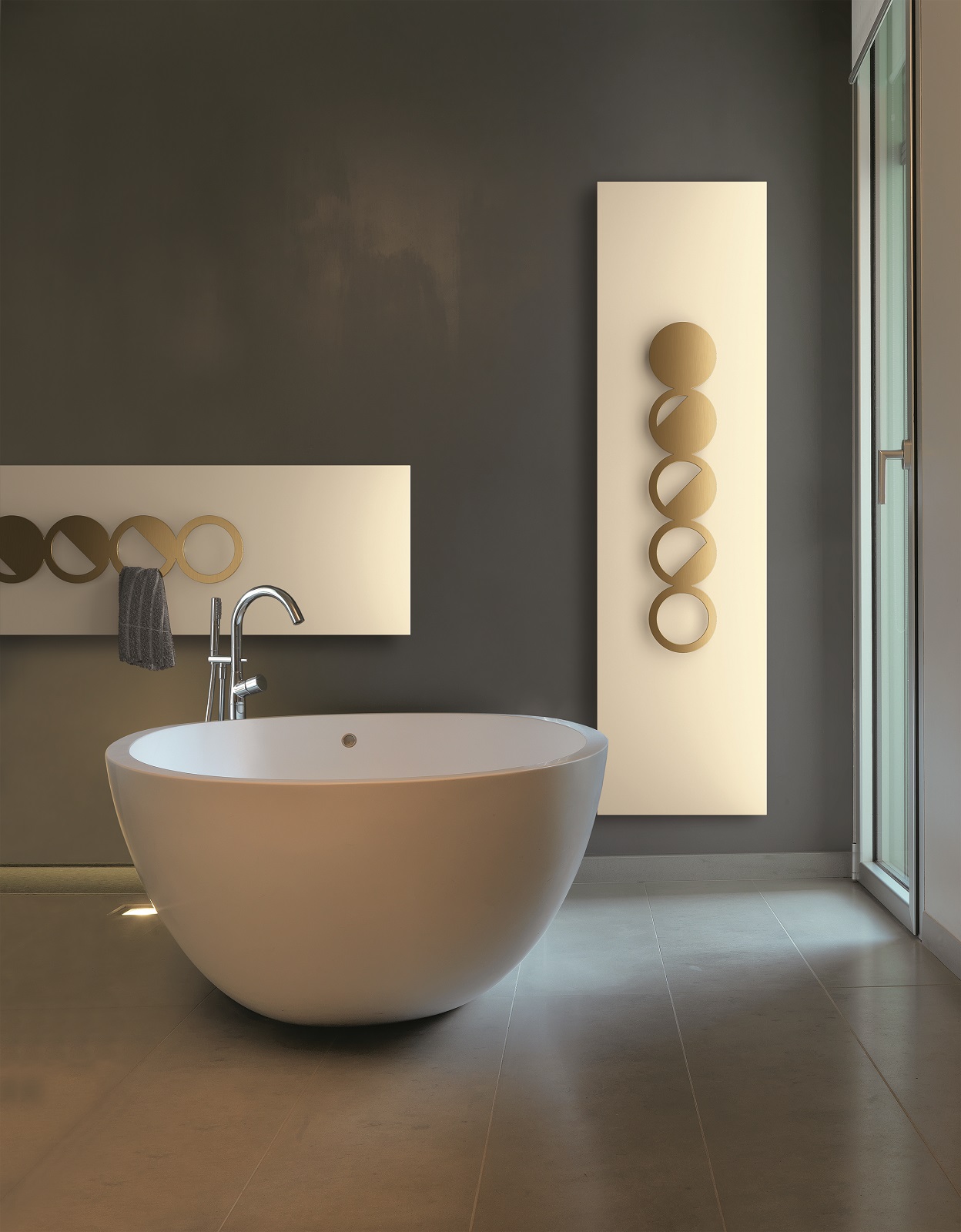 Nature Yin Eclipse di k8 Radiatori è uno scaldasalviette a piastra dotato di un accessorio con appositi spazi per appendere asciugamani e accappatoi. È disponibile in versione idraulica ed elettrica e si può posizionare a muro in orizzontale o verticale. Il cuore è in alluminio estruso mentre cover e accessorio sono in acciaio. Il modello in foto ha una resa termica di 1.144 W, la base è verniciata in bianco crema ral 9001 lucido e ha finitura Oro matt galvanico. Misura L 48 x H 180 cm. Prezzo, Iva esclusa, di questa configurazione 2.169 euro. www.k8radiatori.it