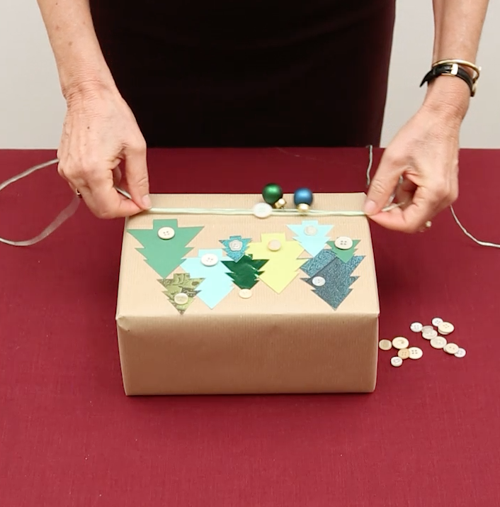 Infilare un bottone di almeno 1,5 cm di diametro e due piccole palline per arricchire i cordoncini di rafia che avvolgerete 2/3 volte alla base del pacchetto Infilare un bottone di almeno 1,5 cm di diametro e due piccole palline per arricchire i cordoncini di rafia che avvolgerete 2/3 volte alla base del pacchetto