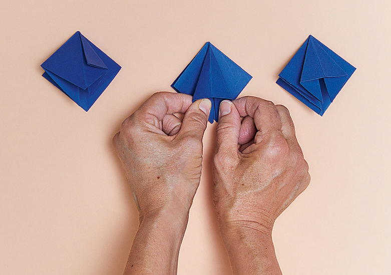 3. Piegare l’angolo di destra verso la linea centrale verticale del rombo, come mostrato in foto, sagoma a sinistra. Ribattere la piega con le dita, aprirla spostandola verso sinistra per ottenere
il triangolo presente sulla sagoma
centrale. Girare la sagoma a rombo
sul retro, e ripetere l’operazione. 3. Piegare l’angolo di destra verso la linea centrale verticale del rombo, come mostrato in foto, sagoma a sinistra. Ribattere la piega con le dita, aprirla spostandola verso sinistra per ottenere
il triangolo presente sulla sagoma
centrale. Girare la sagoma a rombo
sul retro, e ripetere l’operazione.