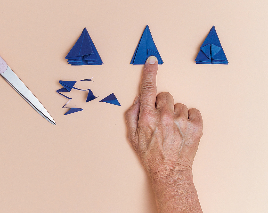 5. Tagliare la parte finale della sagoma così da ottenere un triangolo. Piegare l’angolo di destra verso la linea centrale, come mostrato in foto, ripetere anche con l’angolo di sinistra ribattendo le pieghe con le dita per definirle bene. 5. Tagliare la parte finale della sagoma così da ottenere un triangolo. Piegare l’angolo di destra verso la linea centrale, come mostrato in foto, ripetere anche con l’angolo di sinistra ribattendo le pieghe con le dita per definirle bene.