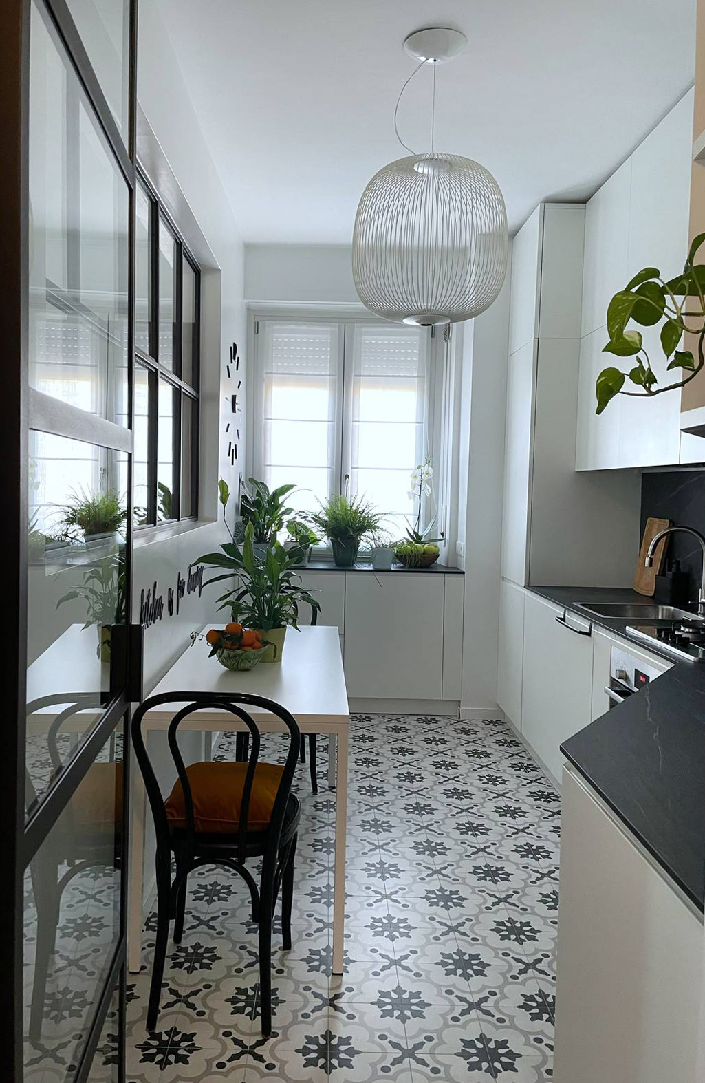 Cucina dopo la ristrutturazione, lineare forma irregolare con top nero e cementine a pavimento bianche e nere Cucina dopo la ristrutturazione, lineare forma irregolare con top nero e cementine a pavimento bianche e nere