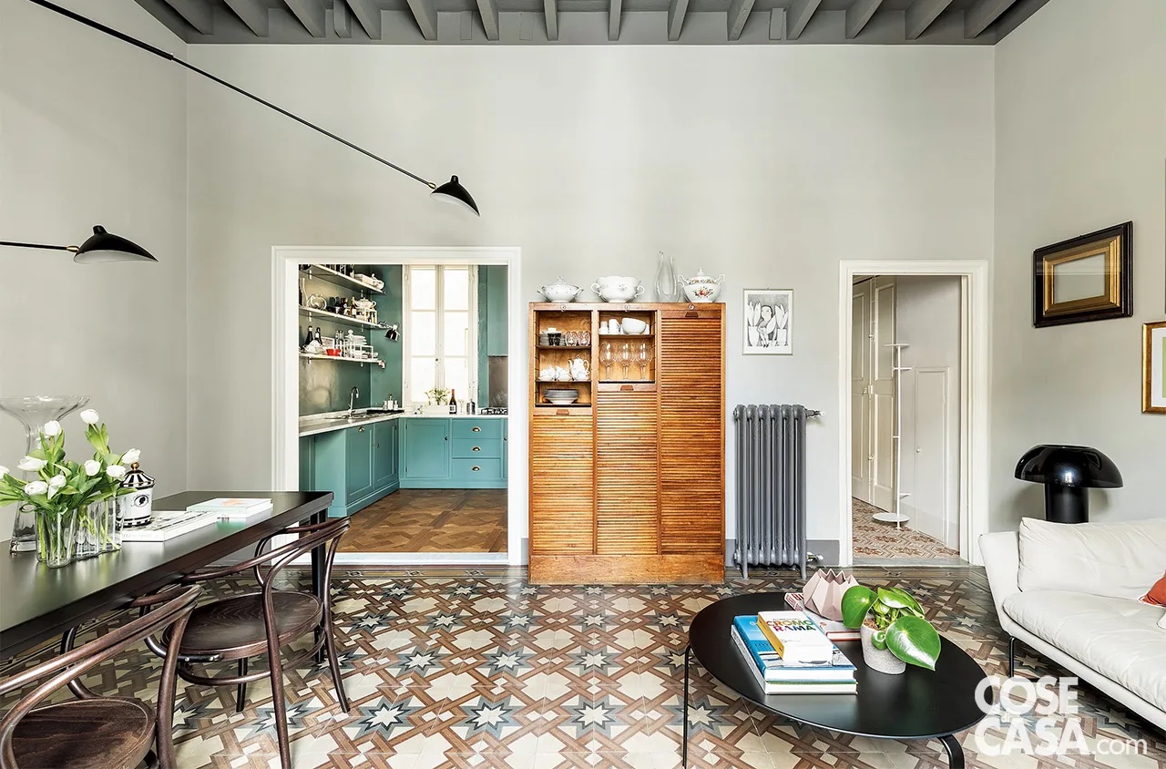 Nell’ambiente con area living e pranzo il pavimento è in cementine, ma in corrispondenza del vano aperto della cucina la soglia in marmo che completa la cornice dello stipite segna il cambio di rivestimento con il passaggio al parquet in rovere massello, posato da Naturae Firenze. La credenza è un pezzo degli anni ’40, la lampada a parete sopra il tavolo da pranzo con bracci di diverse lunghezze e a differenti altezze e diffusori neri è ispirata a Serge Mouille. Il radiatore è stato rinnovato con smalti di Farrow & Ball. Nell’ambiente con area living e pranzo il pavimento è in cementine, ma in corrispondenza del vano aperto della cucina la soglia in marmo che completa la cornice dello stipite segna il cambio di rivestimento con il passaggio al parquet in rovere massello, posato da Naturae Firenze. La credenza è un pezzo degli anni ’40, la lampada a parete sopra il tavolo da pranzo con bracci di diverse lunghezze e a differenti altezze e diffusori neri è ispirata a Serge Mouille. Il radiatore è stato rinnovato con smalti di Farrow & Ball.