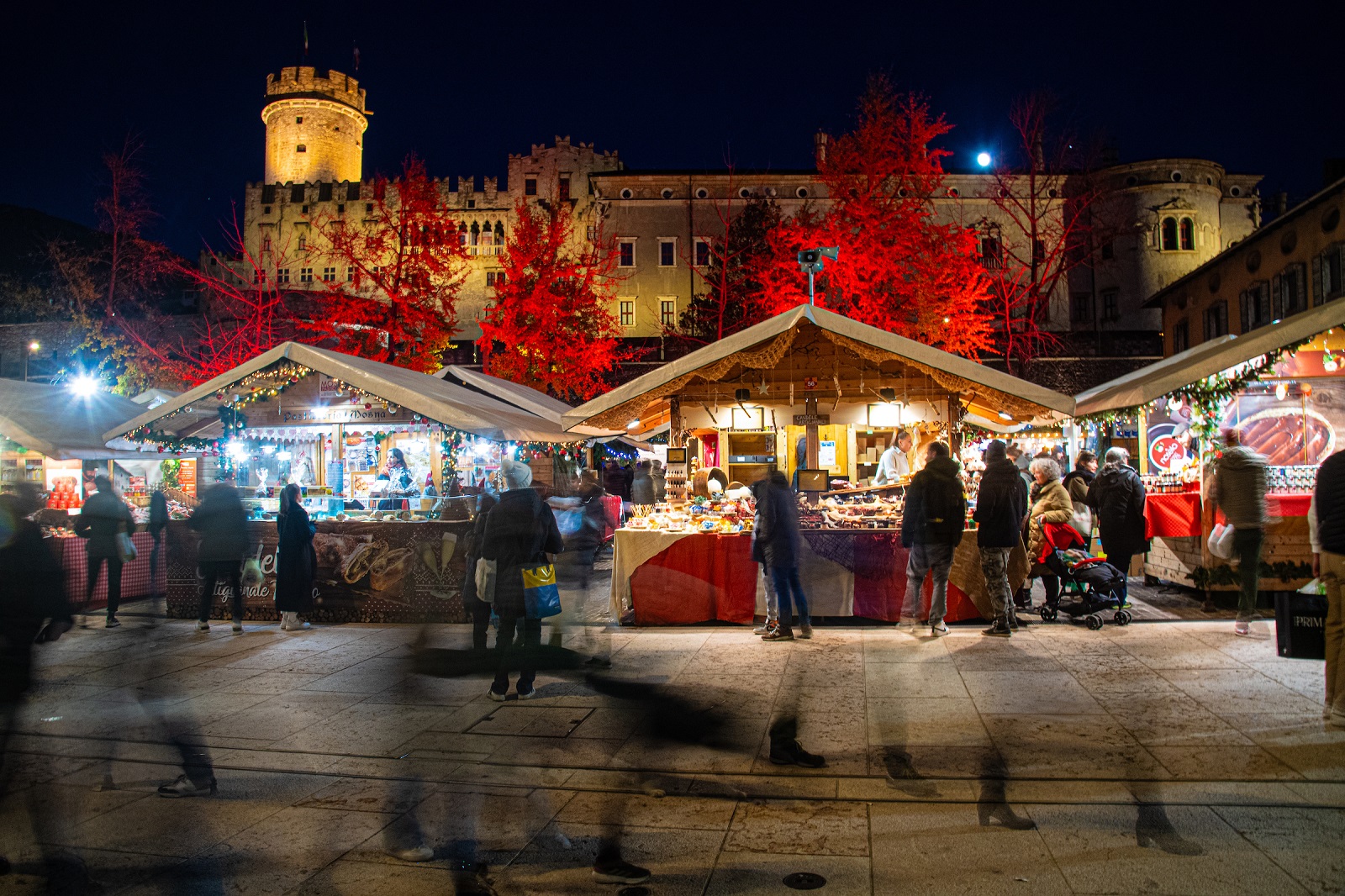 Il Mercatino di Natale di Trento con le sue caratteristiche casette ricche di specialità e prodotti di artigianato si trova nel cuore della città, in Piazza Fiera e in Piazza Mostra. Vi si trovano 74 espositori da tutto il Trentino Alto Adige da cui acquistare ciondoli e addobbi natalizi, alberelli in legno e ceramica, abbigliamento e cosmesi naturale, senza dimenticare cioccolateria, miele e formaggi tipici. Foto: Daniele Mosna_archivio APT Trento. https://natale.trento.info/mercatino e https://www.visittrentino.info/it/guida/mercatini-di-natale/