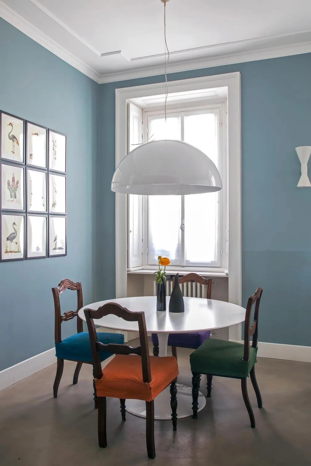 Le sedie in legno con cuscino in tessuto si trovano un po’ in tutte le case, ma quell’aria vecchia oggi non piace più. Ecco il trucco per farle rinascere: sono state fatte confezionare delle fodere per i cuscini in tessuto di cotone a tinte forti, una diversa dall’altra. In alcuni casi si possono anche dipingere la struttura e le gambe, ma qui si è preferito lasciarle in legno scuro, che stacca completamente rispetto al tavolo bianco rotondo, con piano in laminato, di Sarineen, abbinato a una lampada con grande calotta bianca (Sonora di OLuce, design Magistretti): due pezzi di design che creano un insieme chiaro e moderno. Anche la scelta di dipingere le pareti di azzurro polvere contribuisce a creare un insieme attuale. Le sedie in legno con cuscino in tessuto si trovano un po’ in tutte le case, ma quell’aria vecchia oggi non piace più. Ecco il trucco per farle rinascere: sono state fatte confezionare delle fodere per i cuscini in tessuto di cotone a tinte forti, una diversa dall’altra. In alcuni casi si possono anche dipingere la struttura e le gambe, ma qui si è preferito lasciarle in legno scuro, che stacca completamente rispetto al tavolo bianco rotondo, con piano in laminato, di Sarineen, abbinato a una lampada con grande calotta bianca (Sonora di OLuce, design Magistretti): due pezzi di design che creano un insieme chiaro e moderno. Anche la scelta di dipingere le pareti di azzurro polvere contribuisce a creare un insieme attuale.