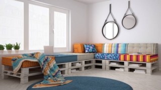 Soggiorno con divano in pallet, in stile scandinavo, perfetto per una casa di vacanza e utilizzabile anche come letto grazie all'uso di cuscini-materasso