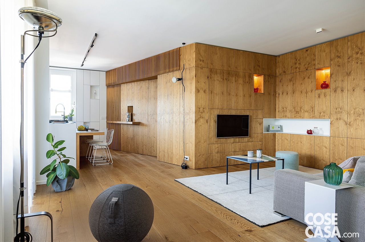 Parete attrezzata in legno che dall'ingresso si prolunga alla zona conversazione Parete attrezzata in legno che dall'ingresso si prolunga alla zona conversazione