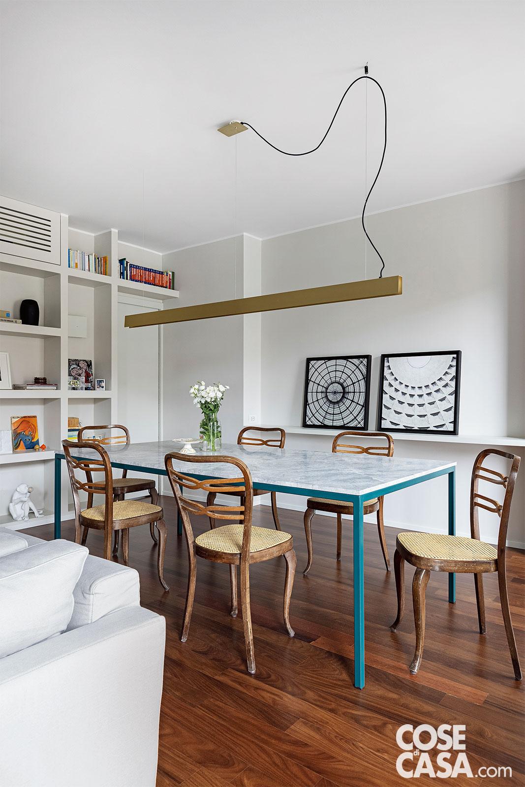 Nella zona pranzo, al centro del living, il tavolo è stato realizzato su disegno, con struttura in metallo blu petrolio e piano nello stesso marmo dell'isola della cucina; le sedie sono di Thonet, modelli vintage di famiglia degli anni '50. Le fotografie in bianco e nero incorniciate, appoggiate sulla mensola a parete, sono di M.Lab 30. La lampada a sospensione in finitura ottone che copre tutta la lunghezza del piano è di Art & Solving. Progetto: LuppettAtelier e Cecilia Avogadro Architetto, Milano. Foto: Cristina Galliena Bohman. Nella zona pranzo, al centro del living, il tavolo è stato realizzato su disegno, con struttura in metallo blu petrolio e piano nello stesso marmo dell'isola della cucina; le sedie sono di Thonet, modelli vintage di famiglia degli anni '50. Le fotografie in bianco e nero incorniciate, appoggiate sulla mensola a parete, sono di M.Lab 30. La lampada a sospensione in finitura ottone che copre tutta la lunghezza del piano è di Art & Solving. Progetto: LuppettAtelier e Cecilia Avogadro Architetto, Milano. Foto: Cristina Galliena Bohman.