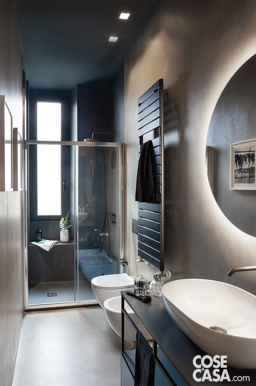 Bagno con rivestimenti in resina e box doccia in fondo al locale