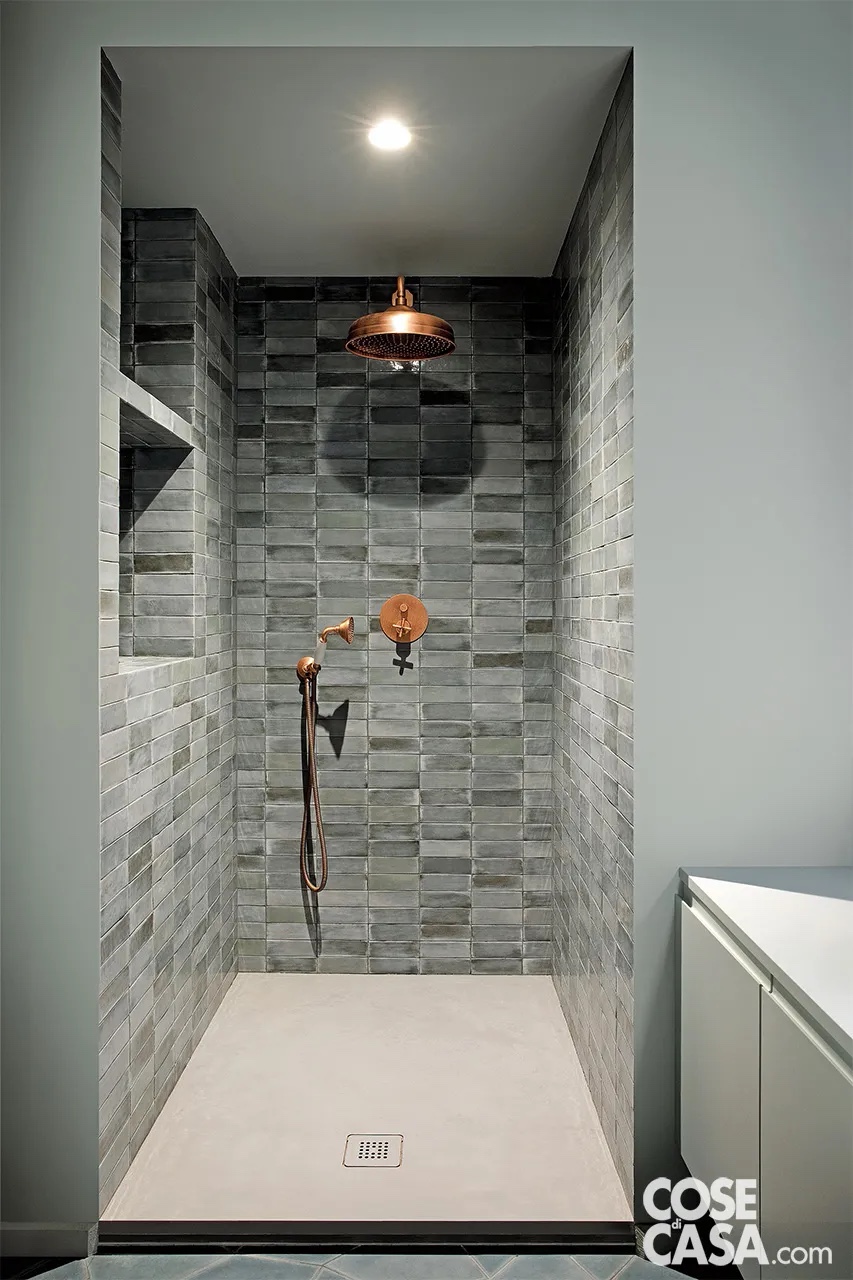 Nel bagno la posizione del box doccia in muratura è obbligata, in quanto definita dall’incrocio di due muri di spina che ne determinano larghezza e profondità. I rivestimenti delle pareti interne sono come quelli dell’altro ambiente di servizio. All’interno del box doccia in muratura le pareti sono rivestite con piastrelle in gres smaltato T-Brick di Sartoria Design. Il piatto doccia in finitura cemento Platinum è di Acquabella. La rubinetteria in finitura rame è della serie Life di Bellosta; il soffione è Life modello Classic. Foto: Barbara Corsico. Styling: Chiara Dal Canto. Progetto: Hom Architetti, arch. Stefania De Paola, arch. Roberta Massetti, arch. Sabrina Saldo con arch. Ottavia Giannone. Nel bagno la posizione del box doccia in muratura è obbligata, in quanto definita dall’incrocio di due muri di spina che ne determinano larghezza e profondità. I rivestimenti delle pareti interne sono come quelli dell’altro ambiente di servizio. All’interno del box doccia in muratura le pareti sono rivestite con piastrelle in gres smaltato T-Brick di Sartoria Design. Il piatto doccia in finitura cemento Platinum è di Acquabella. La rubinetteria in finitura rame è della serie Life di Bellosta; il soffione è Life modello Classic. Foto: Barbara Corsico. Styling: Chiara Dal Canto. Progetto: Hom Architetti, arch. Stefania De Paola, arch. Roberta Massetti, arch. Sabrina Saldo con arch. Ottavia Giannone.