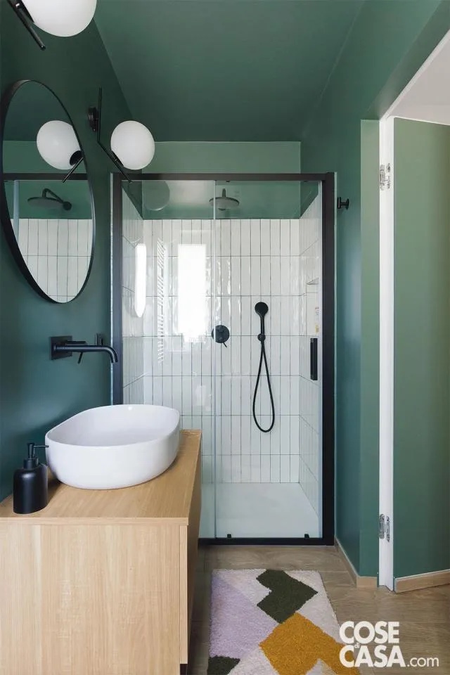 Piccolo bagno di servizio con pavimento in gres porcellanato effetto legno e pareti e plafone verde con accenti in nero – complementi, luci, rubinetti, contrapposti al bianco di sanitari e piastrelle nella doccia con fughe verdi in evidenza coordinate. Piccolo bagno di servizio con pavimento in gres porcellanato effetto legno e pareti e plafone verde con accenti in nero – complementi, luci, rubinetti, contrapposti al bianco di sanitari e piastrelle nella doccia con fughe verdi in evidenza coordinate.