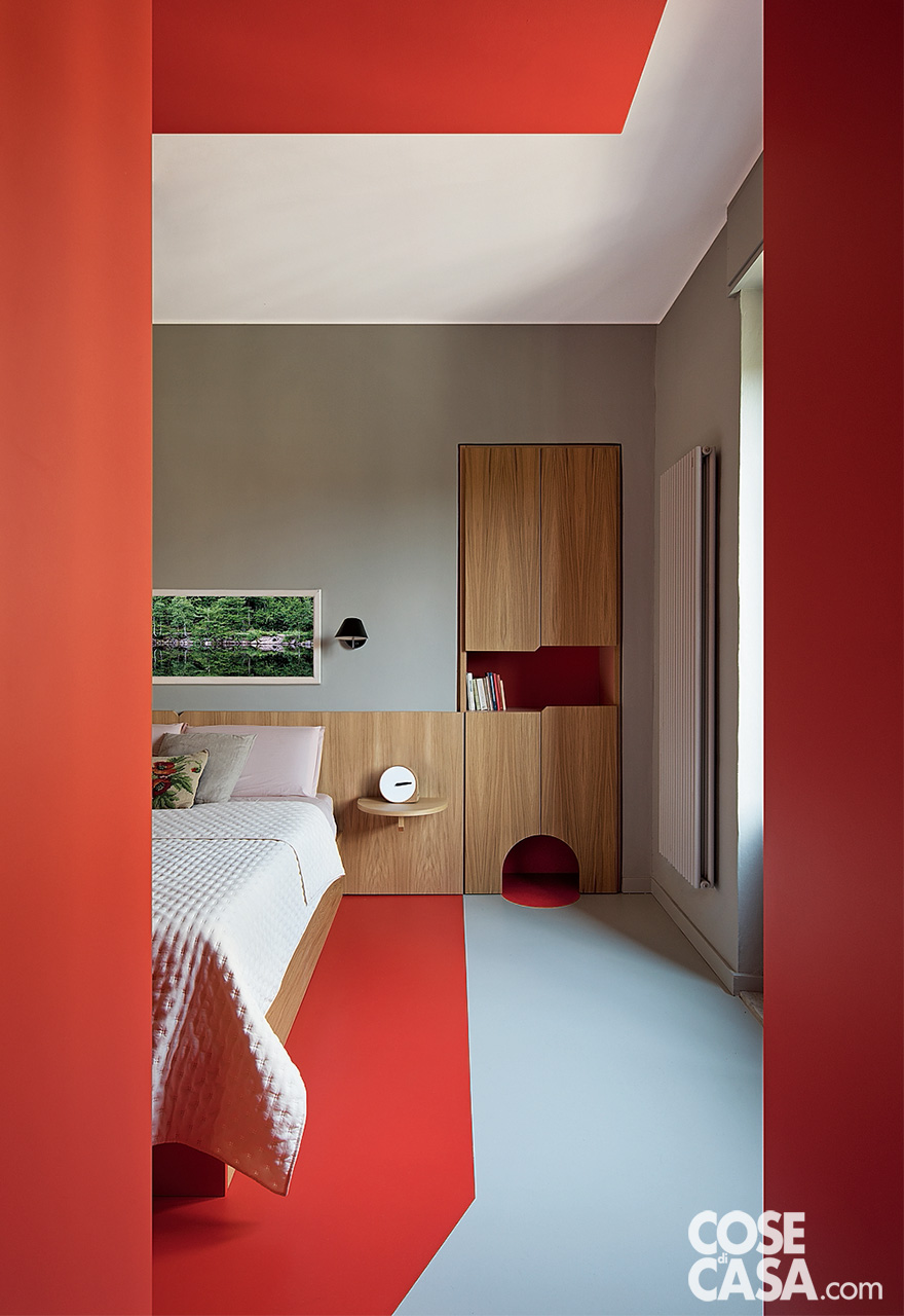 camera con letto in legno chiaro e pavimeto rosso