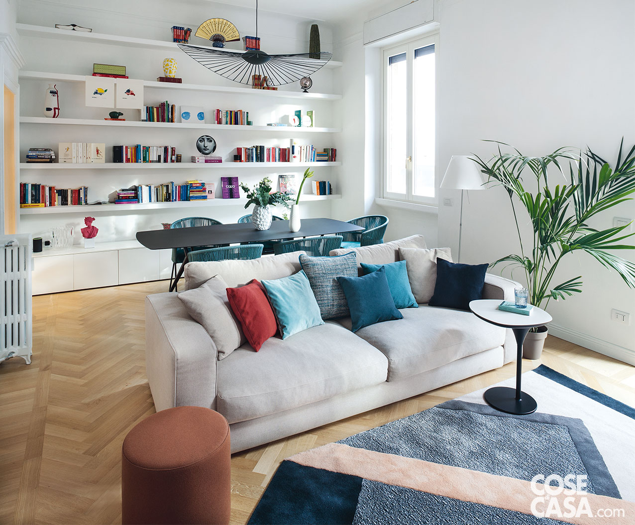 Soggiorno con libreria a tutta parete, tavolo e divano al centro dell'ambiente