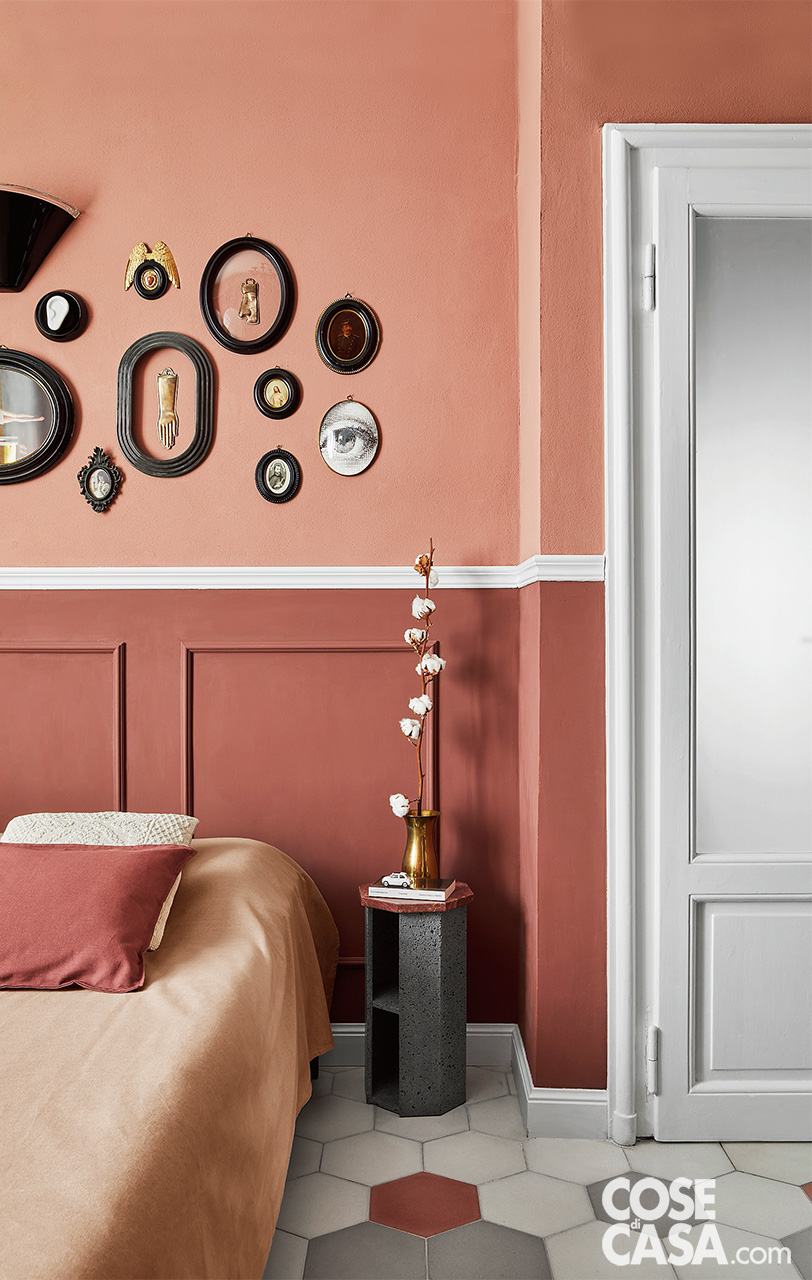 Camera da letto con boiserie rosa e rosso antichi e oggetti decorativi a parete