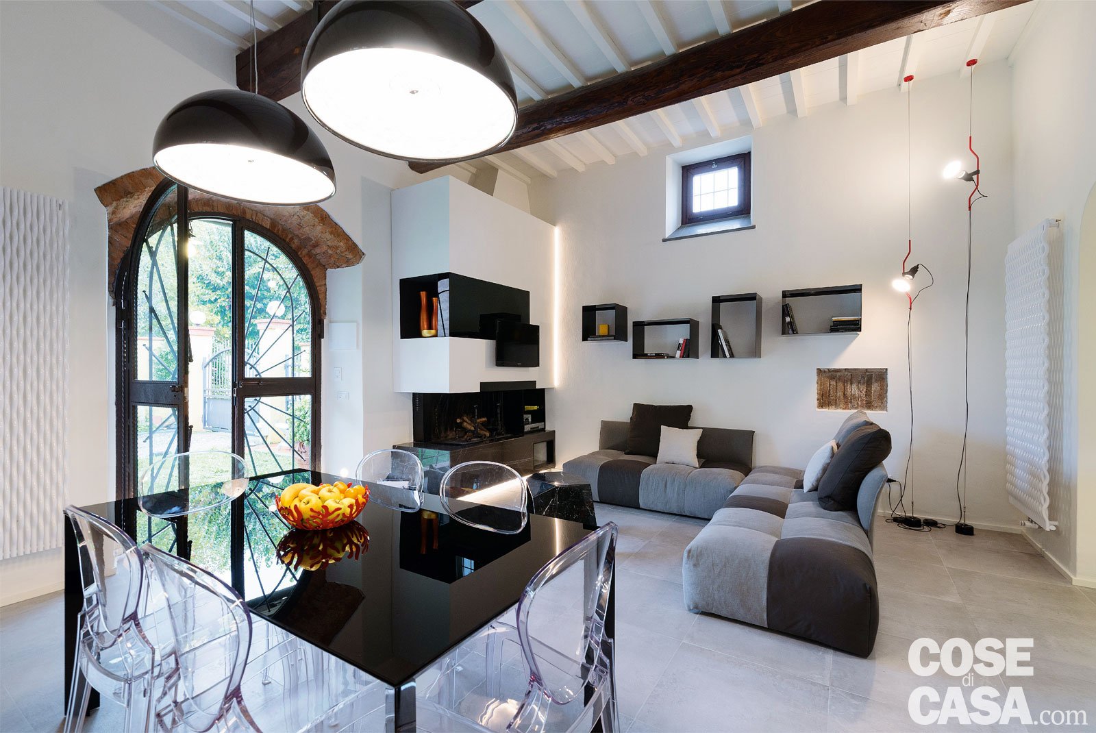 Un living contemporaneo tra bianco e nero in una antica casa colonica toscana ristrutturata, con un netto contrasto tra chiaro e scuro. Restano però inalterati alcuni dettagli classici in versione rustica,  come l’arco della portafinestra, che affaccia sul giardino - Foto: Darragh Hehir. Progetto: B + P architetti Pierluigi Percoco e Alessia Bettazzi.