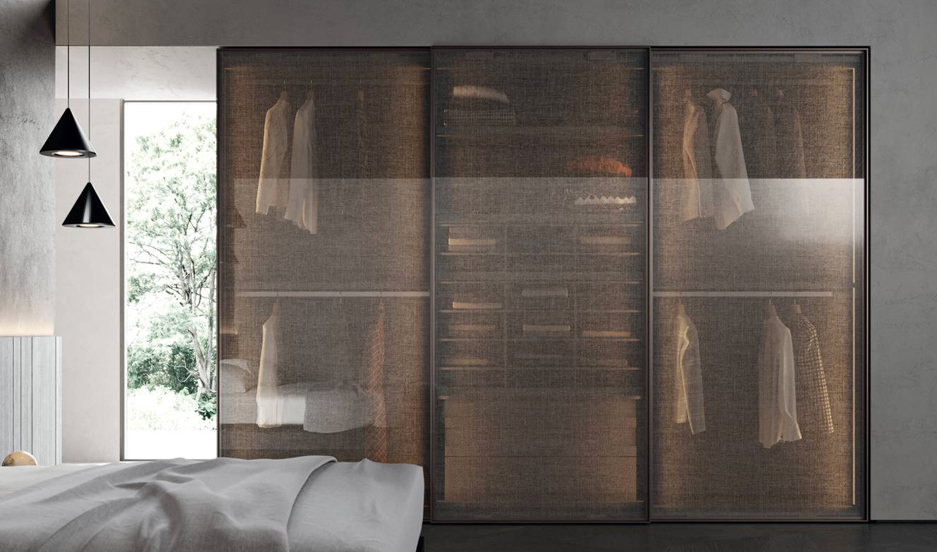 Le ante scorrevoli Look trasformano l'armadio di Tumidei, dotato di chiusura rallentata ad azione magnetica, in una sorta di scrigno prezioso: sono realizzate in vetro temperato trasparente extrachiaro e tessuto in rilievo semitrasparente 04 Oak con il telaio in alluminio color bronzo. All'interno sono presenti tubi appendiabiti, cassettiere e elementi multivano; inoltre, l'illuminazione interna lo rende scenografico. Misura L 356,2 x P 68 x H 263 cm. Prezzo a partire da 9.300 euro. www.tumidei.it Le ante scorrevoli Look trasformano l'armadio di Tumidei, dotato di chiusura rallentata ad azione magnetica, in una sorta di scrigno prezioso: sono realizzate in vetro temperato trasparente extrachiaro e tessuto in rilievo semitrasparente 04 Oak con il telaio in alluminio color bronzo. All'interno sono presenti tubi appendiabiti, cassettiere e elementi multivano; inoltre, l'illuminazione interna lo rende scenografico. Misura L 356,2 x P 68 x H 263 cm. Prezzo a partire da 9.300 euro. www.tumidei.it