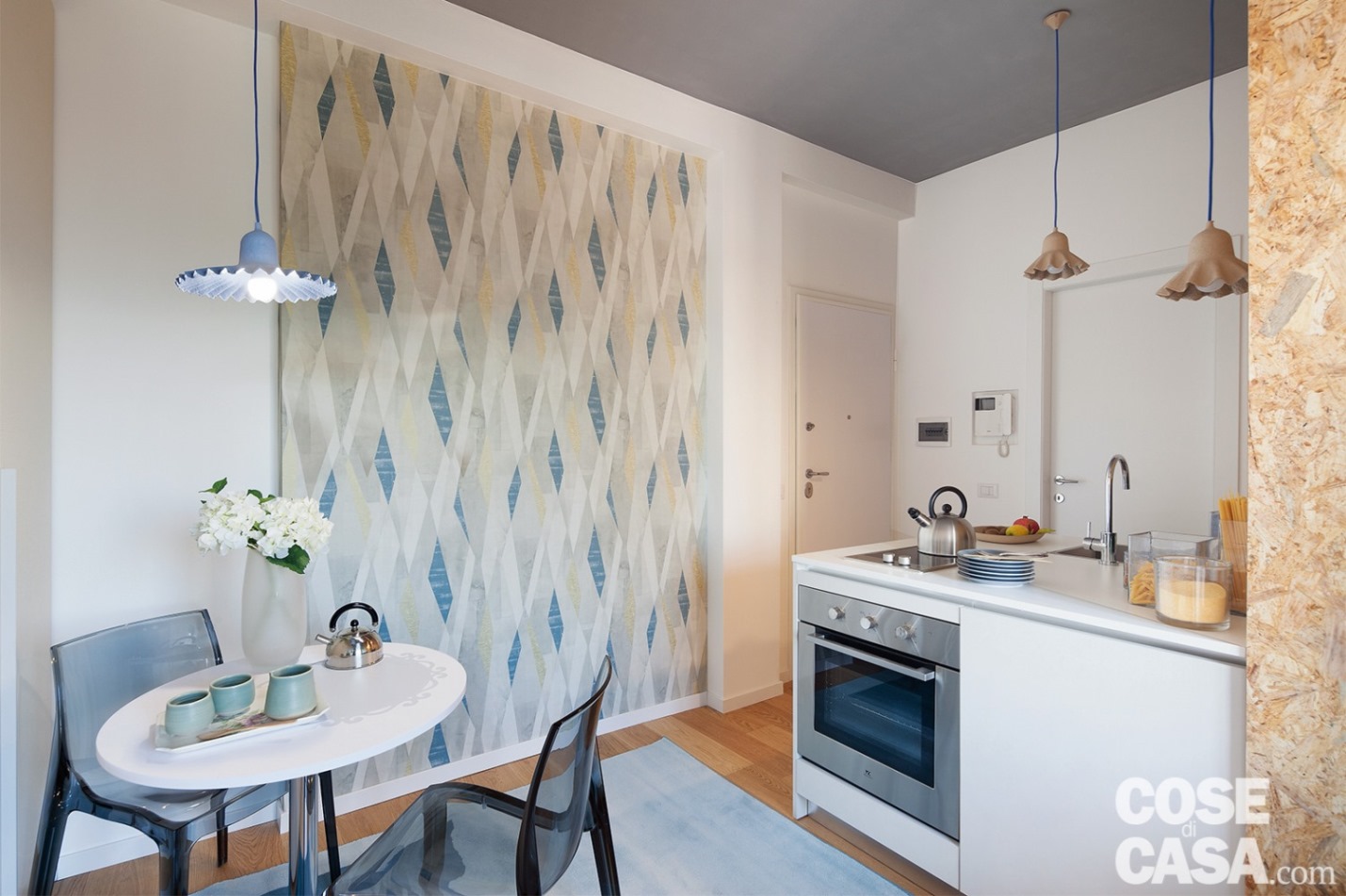 La piccola cucina e il tavolino tondo sono abbellite da lampade a sospensione Egg of Columbus di Seletti di vari colori e dimensioni, realizzate in cartone riciclato, che richiamano cromaticamente la tappezzeria a parete - Foto: Cristina Fiorentini. Progetto di Interior Decoration: Salvina Bosco.