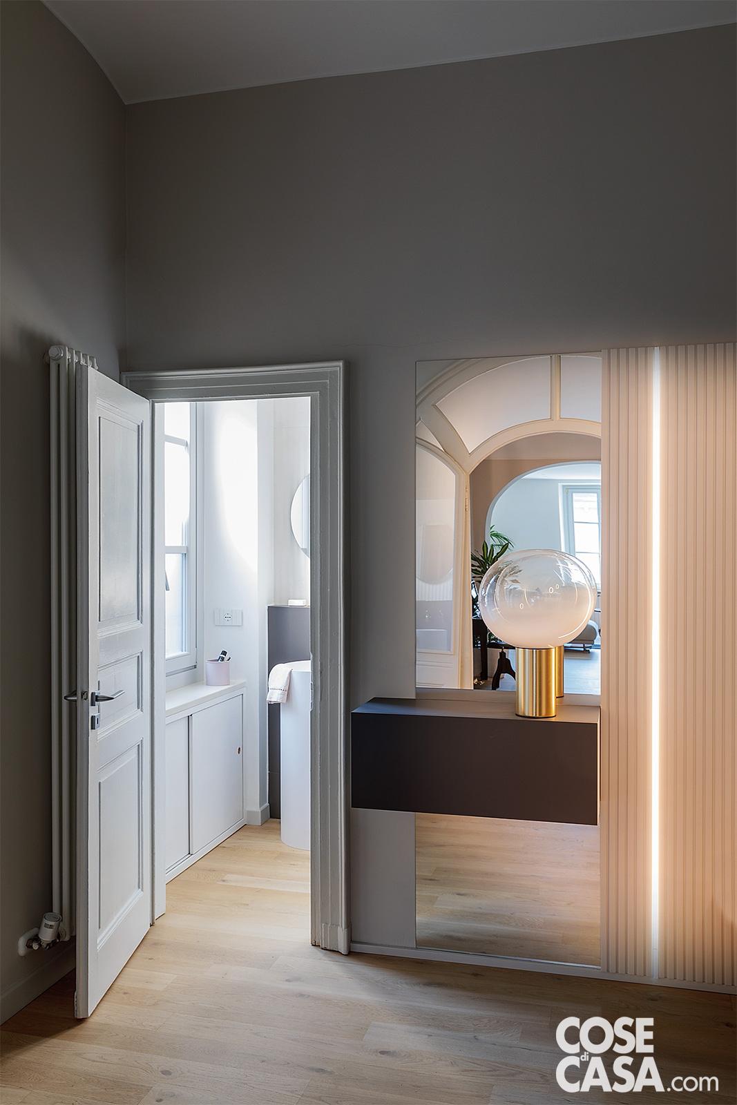 Anche l’ingresso vuole la sua parte e si prende la scena con pochi ma giusti elementi di design, come la lampada Laguna di Artemide, con base in ottone e diffusore a sfera, che sovrasta la consolle e affianca la boiserie – Foto: Claudio Tajoli. Styling: Rosaria Galli. Progetto: Sferico architetti.