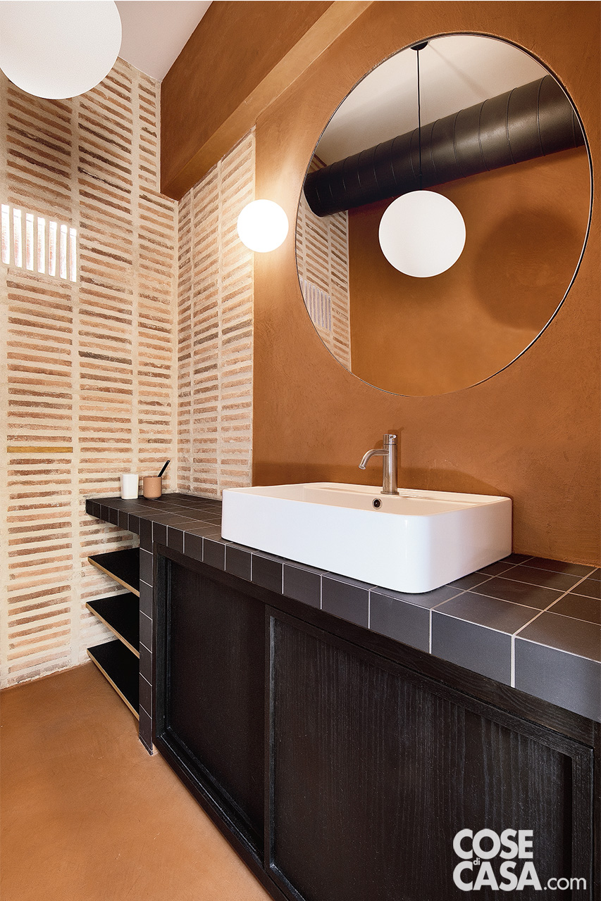 bagno con lavabo su struttura in muratura e piastrelle nere