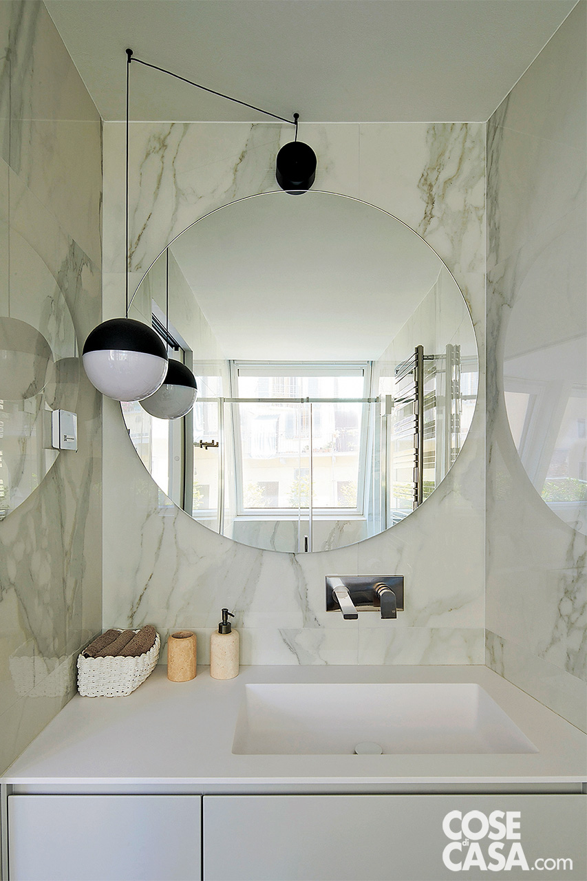 Bagno in camera con rivestimenti in marmo e specchio rotondo Bagno in camera con rivestimenti in marmo e specchio rotondo