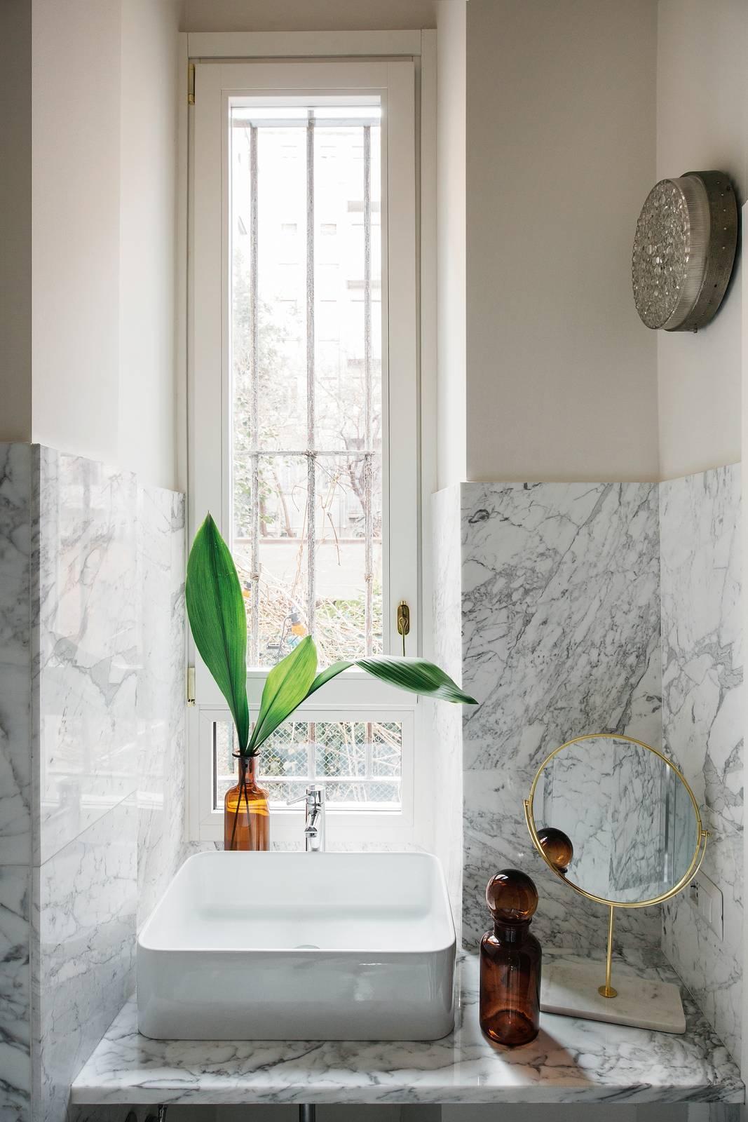Il rivestimento a parete in marmo chiaro nel bagno sotto finestra moltiplica la luce naturale proveniente dall'apertura accentuando anche la sensazione di ariosità del locale. Progetto: Studio A/C, Milano. Foto: Studio Roy