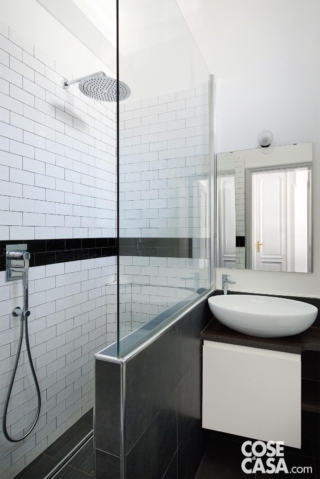 Bianco e nero, con fughe a contrasto e piastrelle rettangolari posate come mattoni faccia a vista, il piccolo bagno viene sfruttato al massimo anche grazie alla soluzione della doccia in muratura e della zona lavabo contigue. La doccia walk-in è delimitata da un muro basso completato da una vetrata trasparente. Progetto: arch. Nicoletta Carbotti in collaborazione con arch. Emma Cavigliasso, FattoreQ | fabbrica, Torino – https://www.fattoreq.com - Foto: Barbara Corsico. Styling: Chiara Dal Canto.