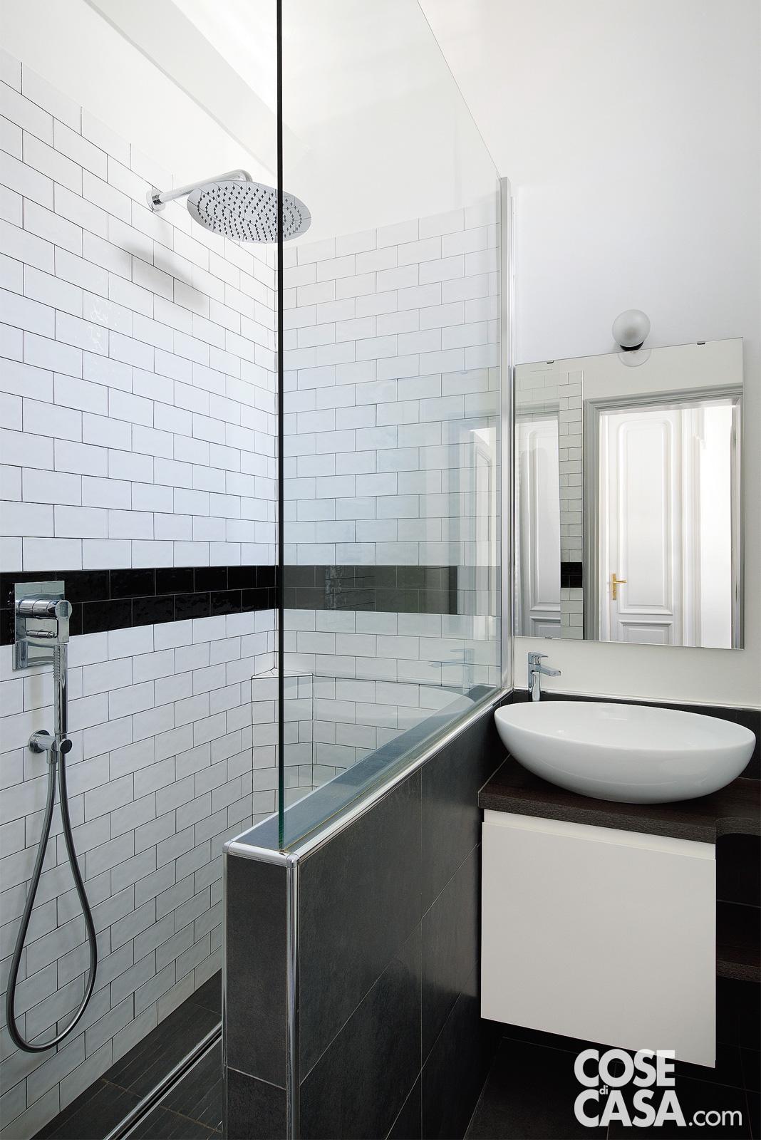 Bianco e nero, con fughe a contrasto e piastrelle rettangolari posate come mattoni faccia a vista, il piccolo bagno viene sfruttato al massimo anche grazie alla soluzione della doccia in muratura e della zona lavabo contigue. La doccia walk-in è delimitata da un muro basso completato da una vetrata trasparente. Progetto: arch. Nicoletta Carbotti in collaborazione con arch. Emma Cavigliasso, FattoreQ | fabbrica, Torino – https://www.fattoreq.com - Foto: Barbara Corsico. Styling: Chiara Dal Canto.