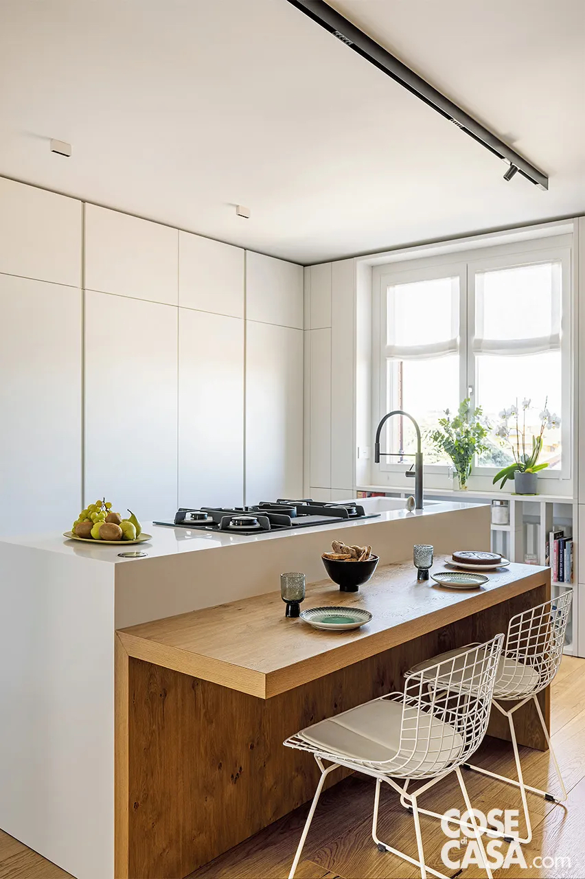 Cucina bianca con isola e banco snack ribassato in legno
